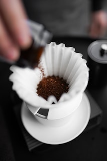 A person pours coffee into a white cup