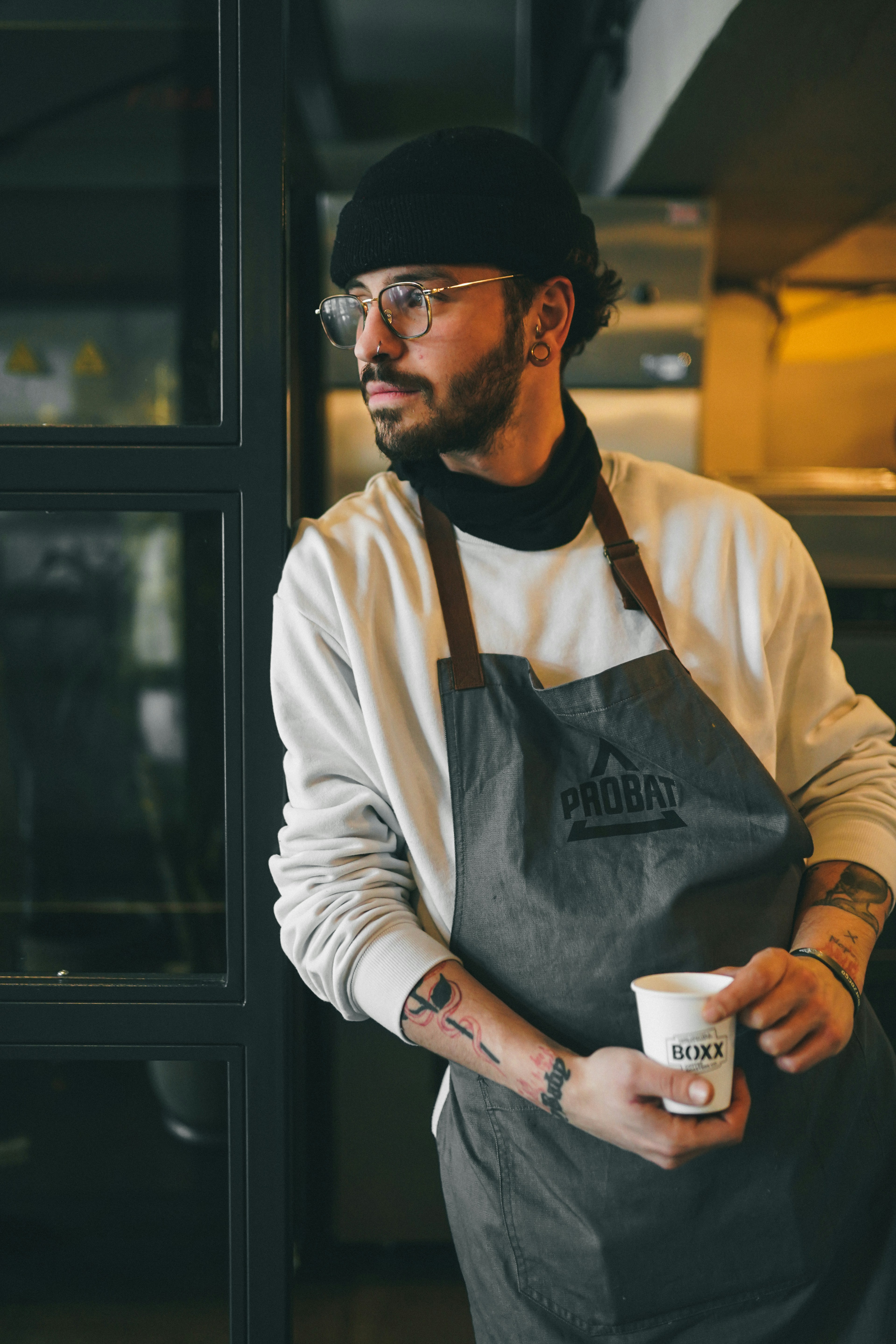 A man in an apron holding a cup of coffee