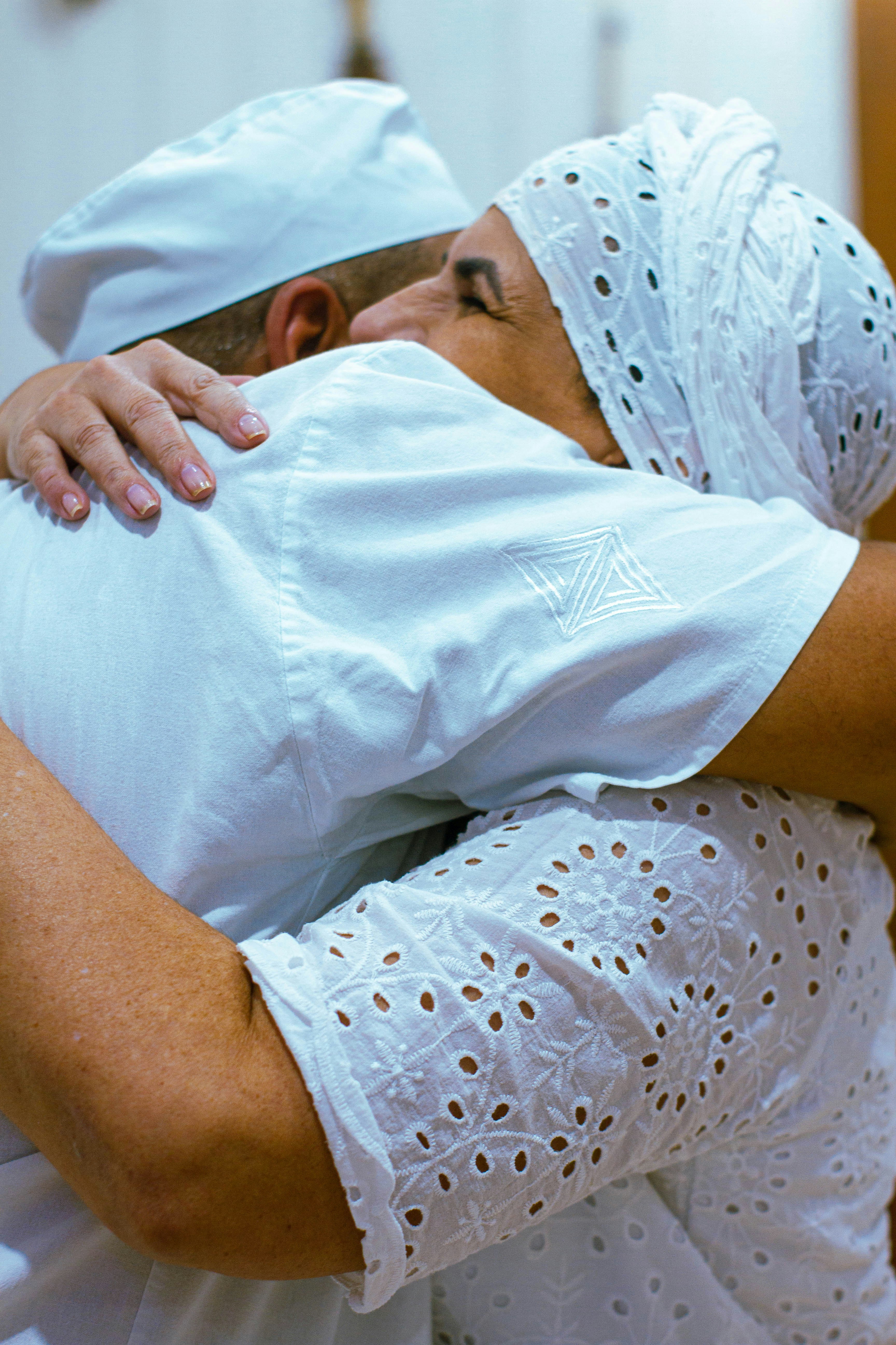 Un hombre con camisa blanca y sombrero abrazando a una mujer