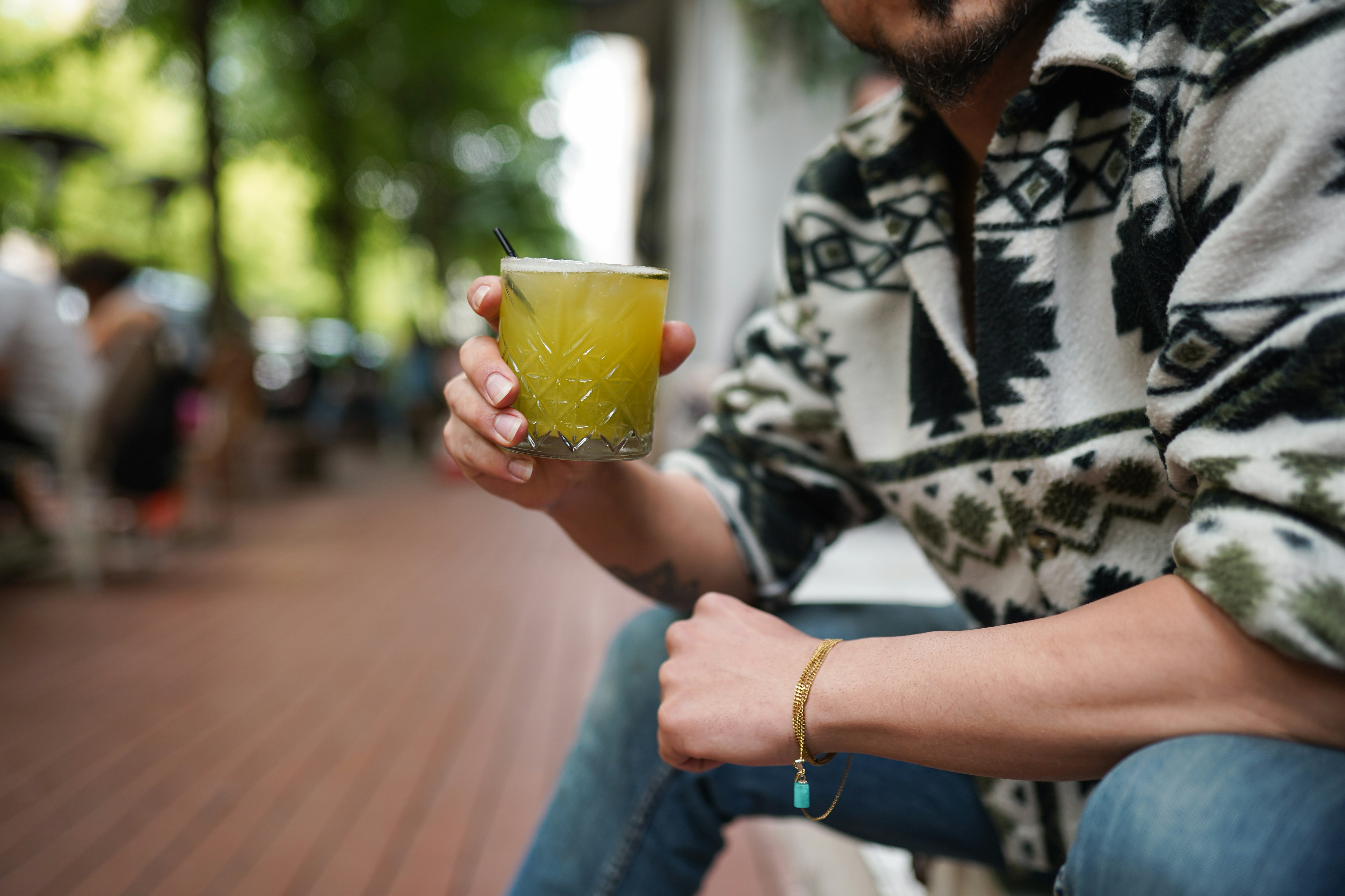 A man sitting on a bench holding a drink