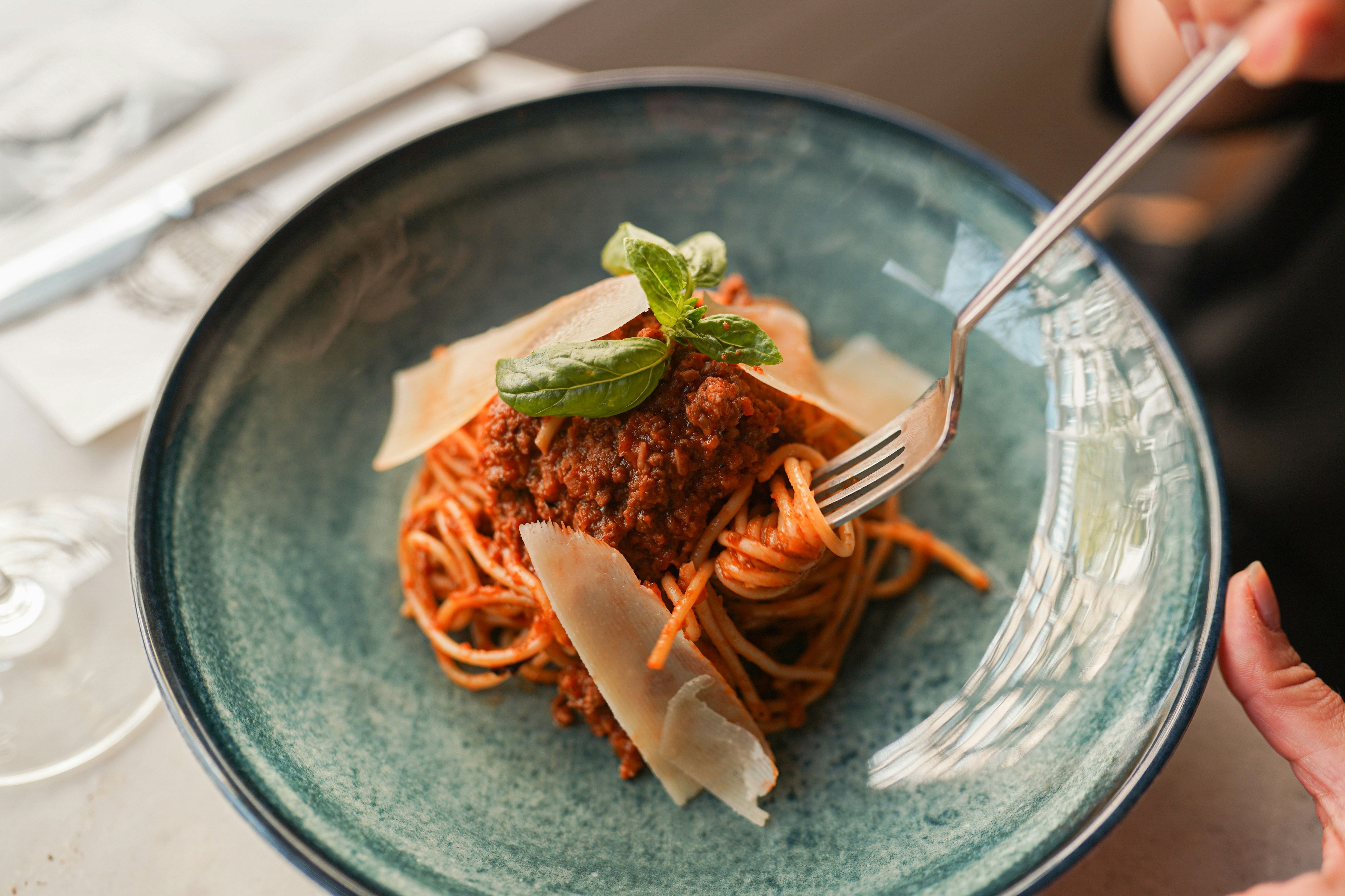 A person holding a fork and a plate of spaghetti