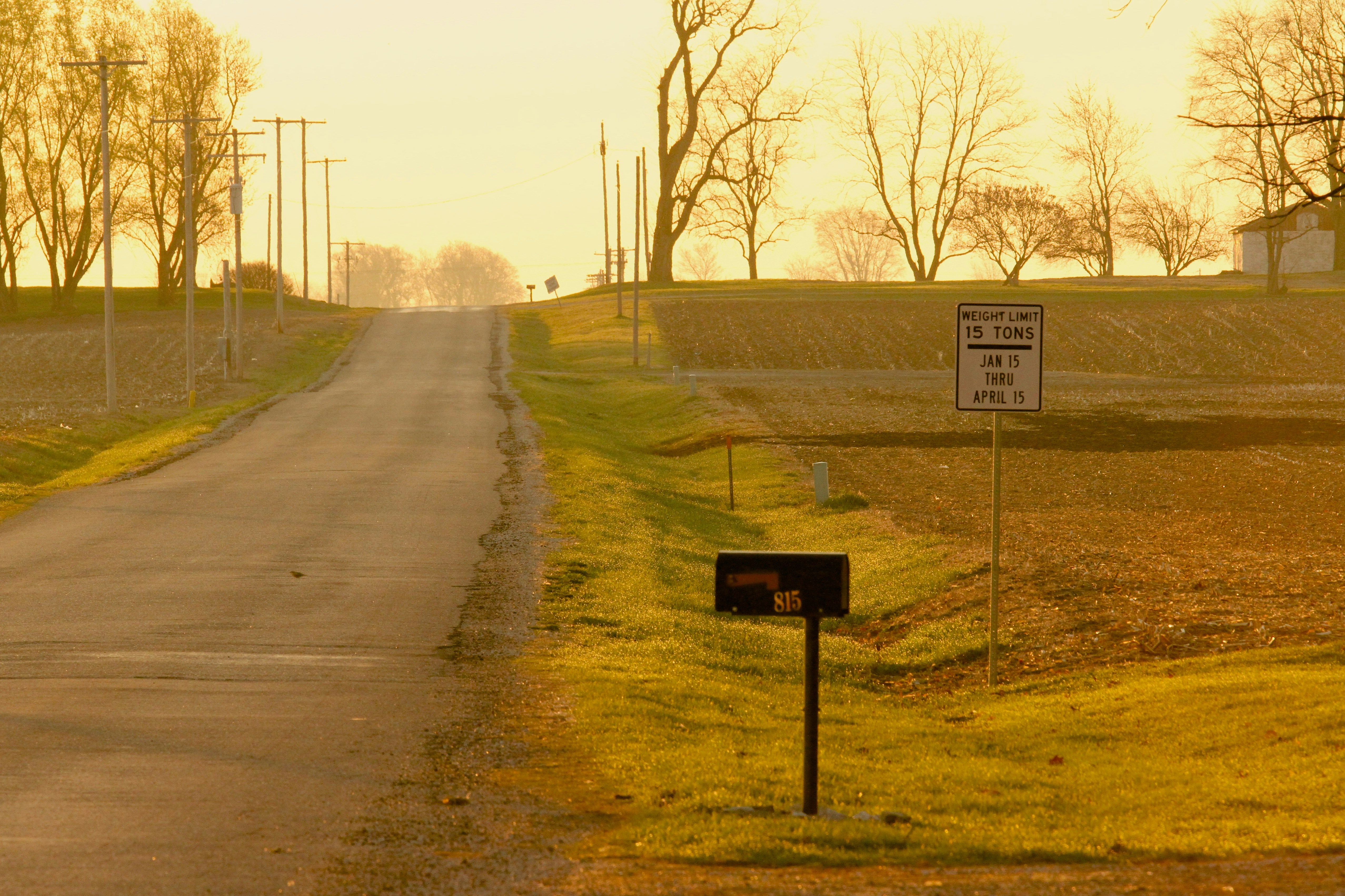 A rural road with a sign on the side of it