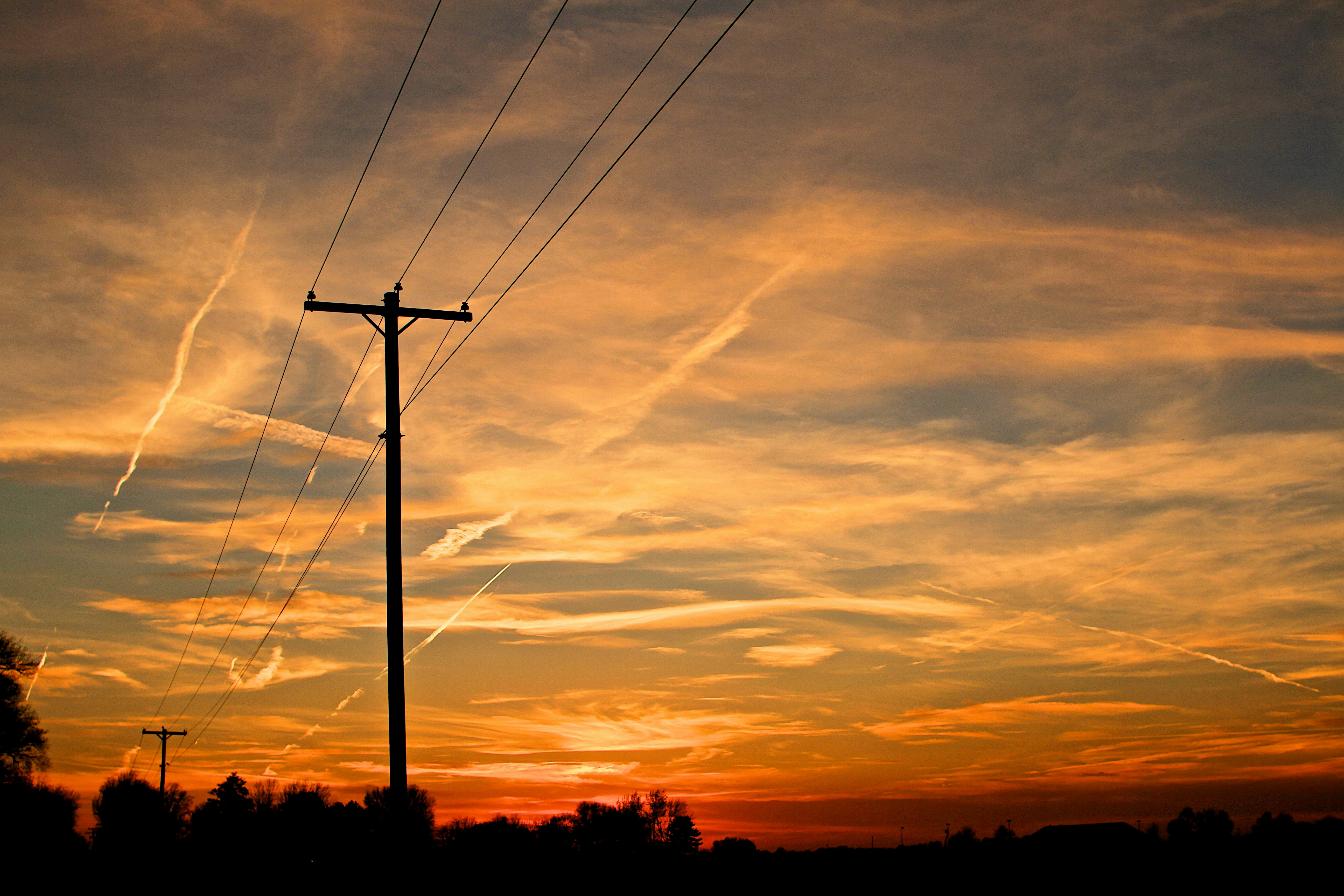 The sun is setting behind a telephone pole