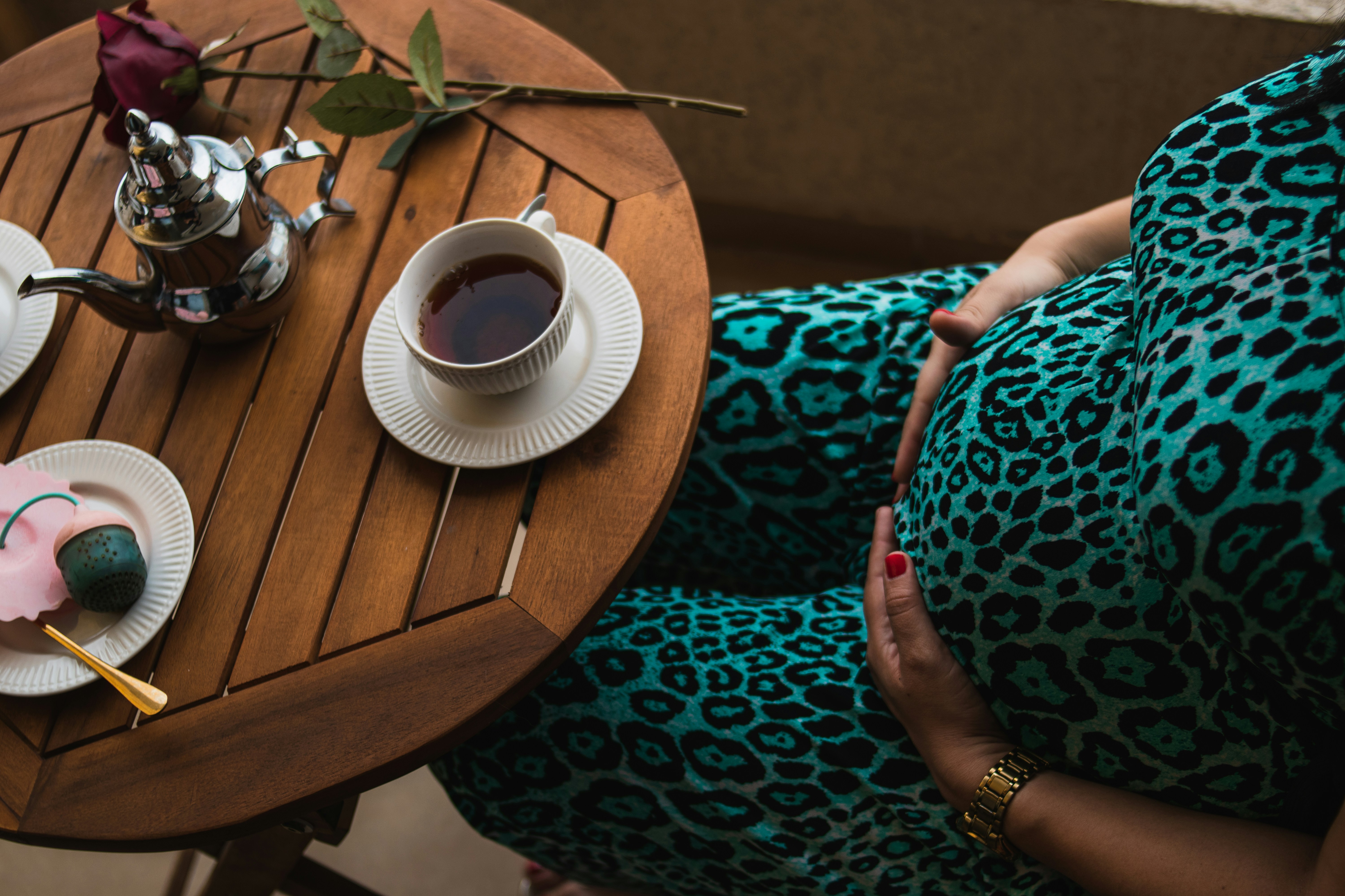 Pregnant woman with a mug of tea or coffee, illustrating moderate caffeine intake during pregnancy.