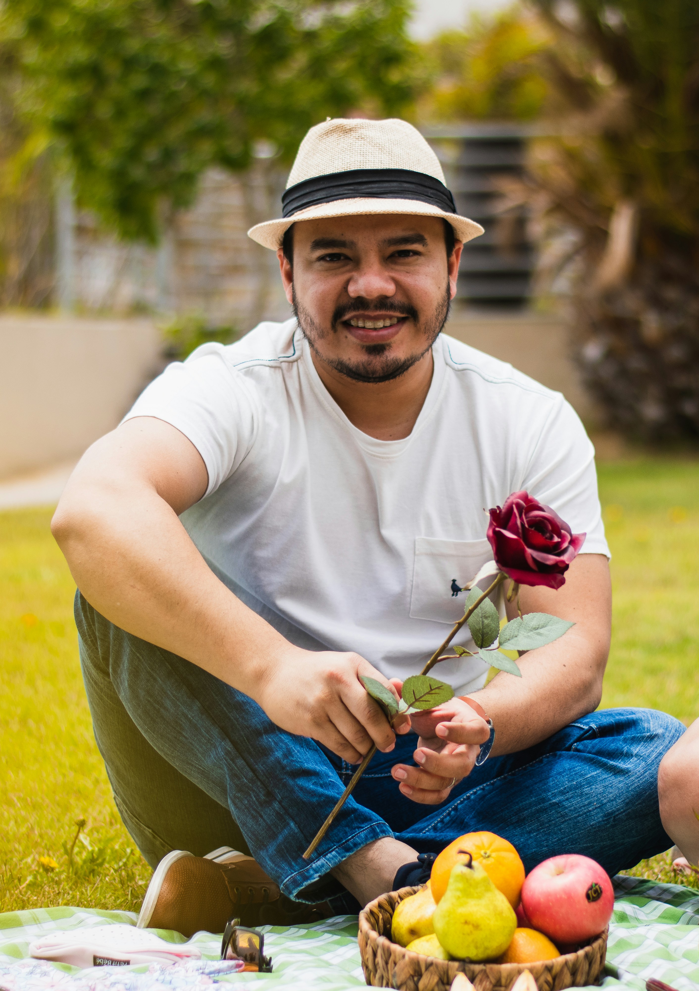 Ein Mann sitzt auf einer Decke und hält eine Rose in der Hand