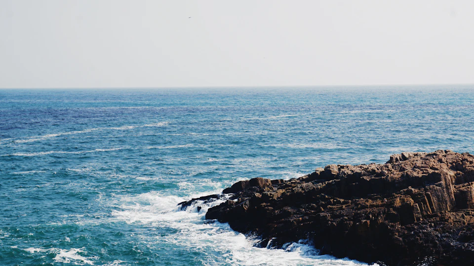 Serene ocean scene with rocky cliff overlooking vast expanse of deep blue water