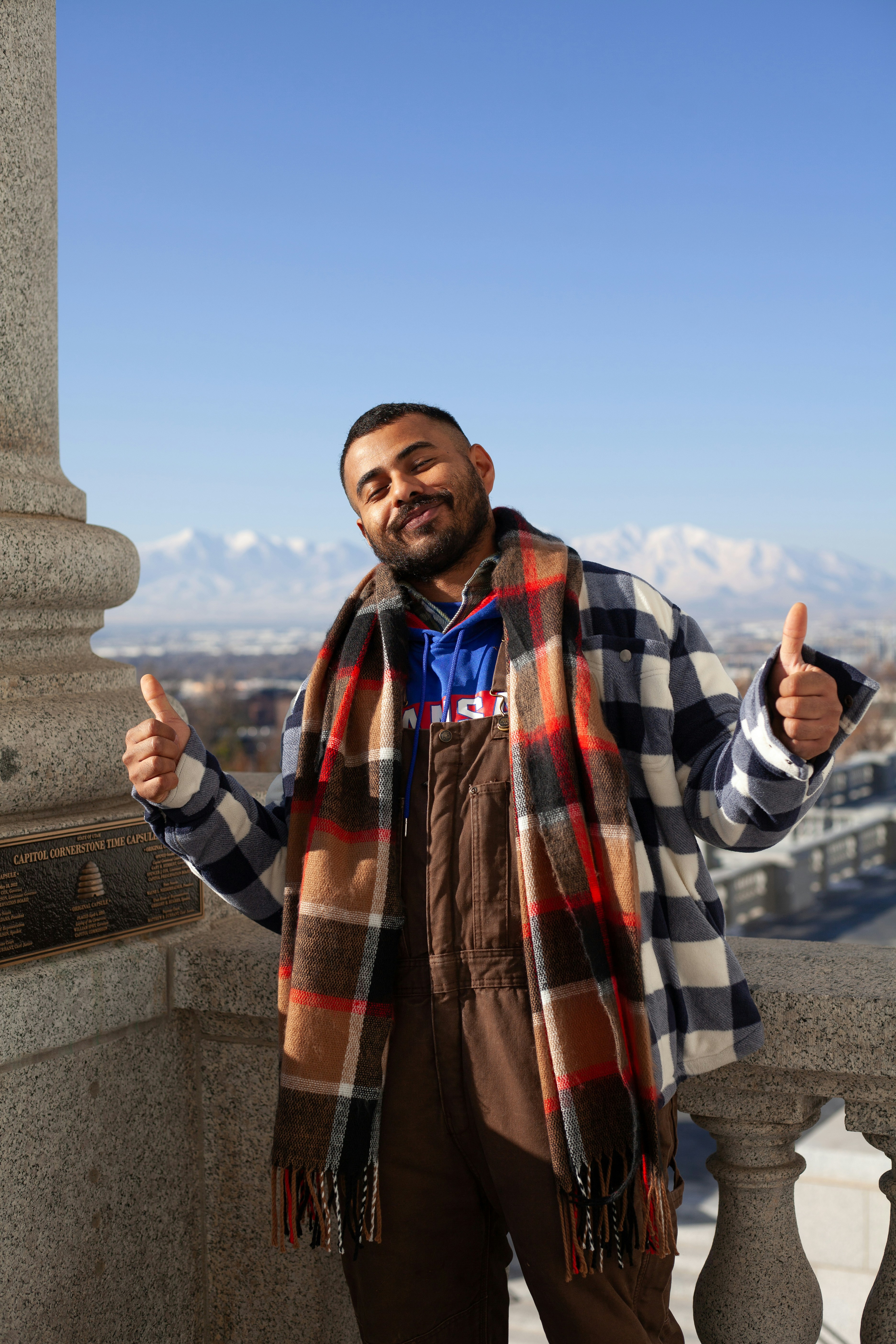 A man standing on top of a building with a scarf around his neck