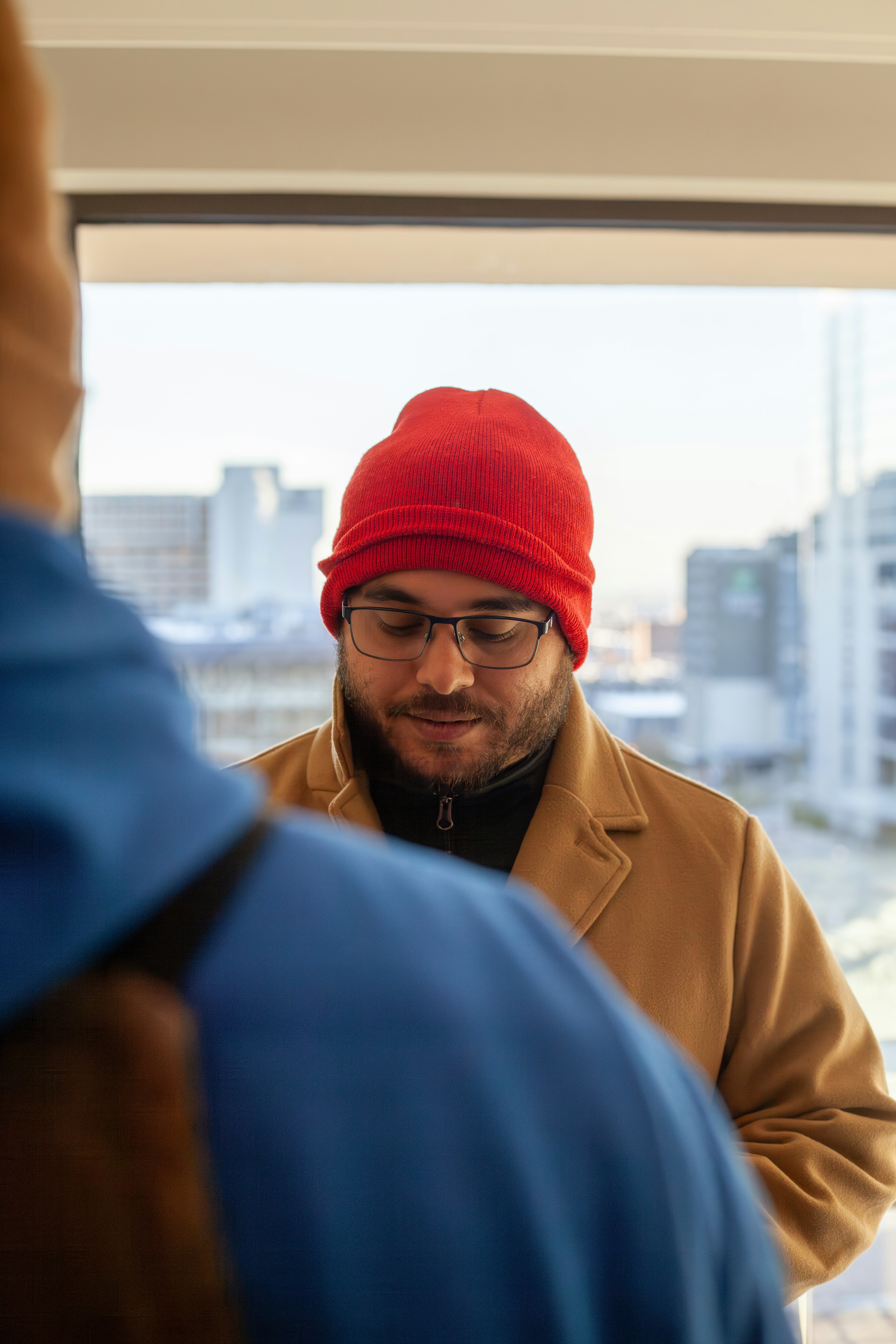 A man wearing a red beanie looking at his cell phone