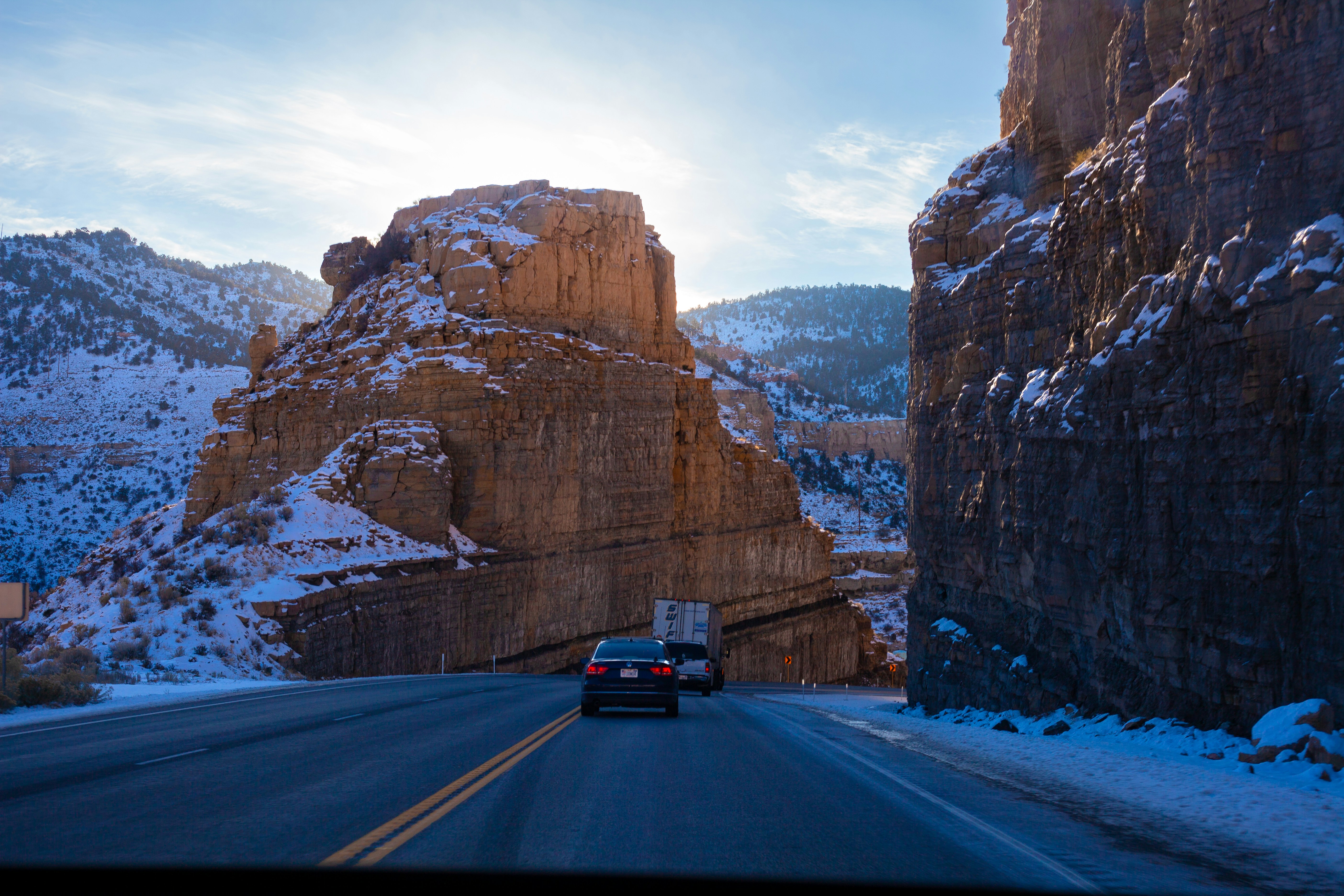 A car driving down a road next to a mountain