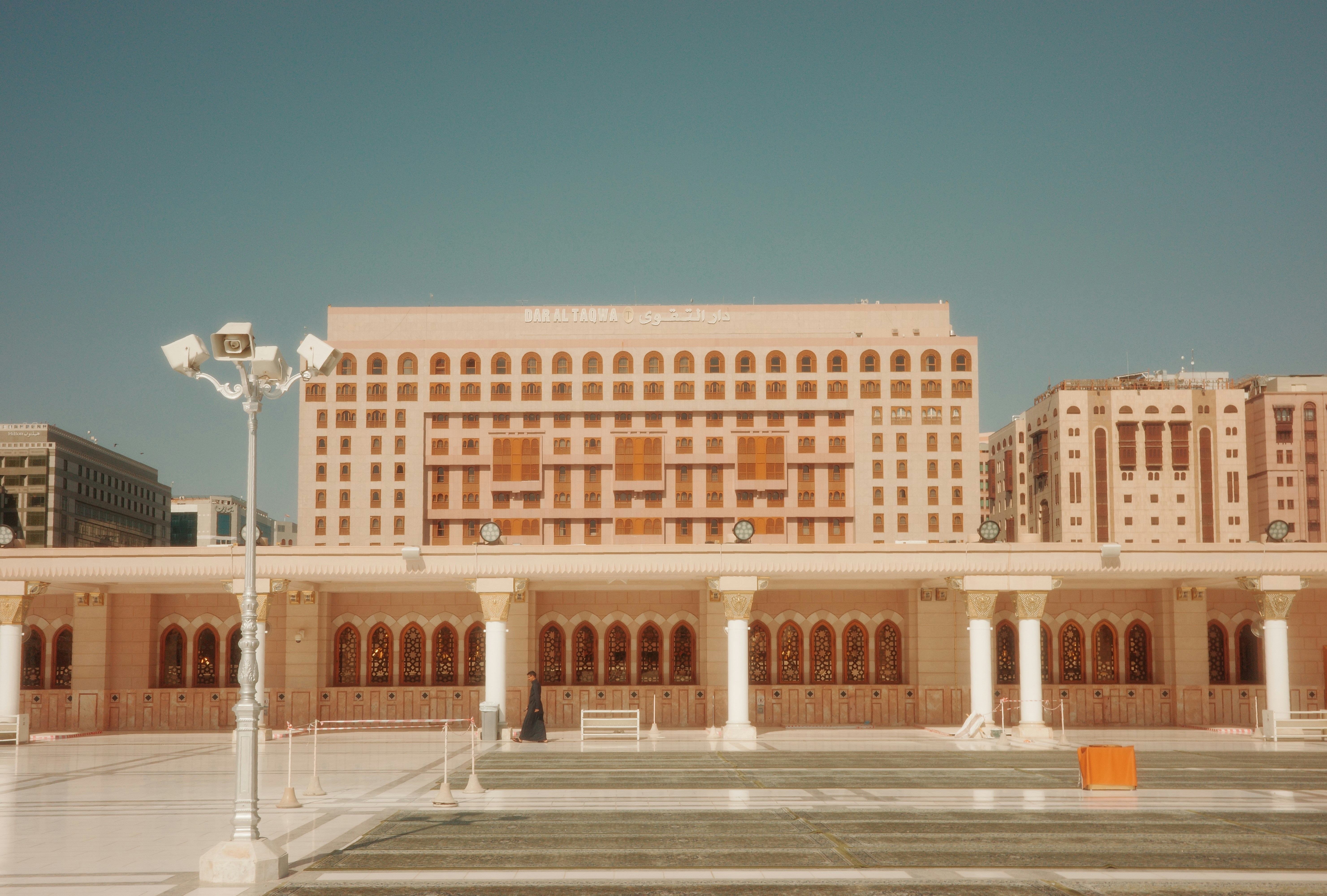 A somber photo of the Indian embassy building in Saudi Arabia, possibly with a worried crowd blurred in the foreground.