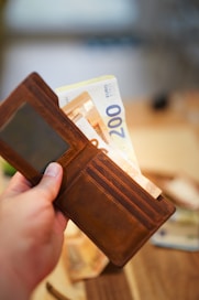 A person is holding a wallet with money in it