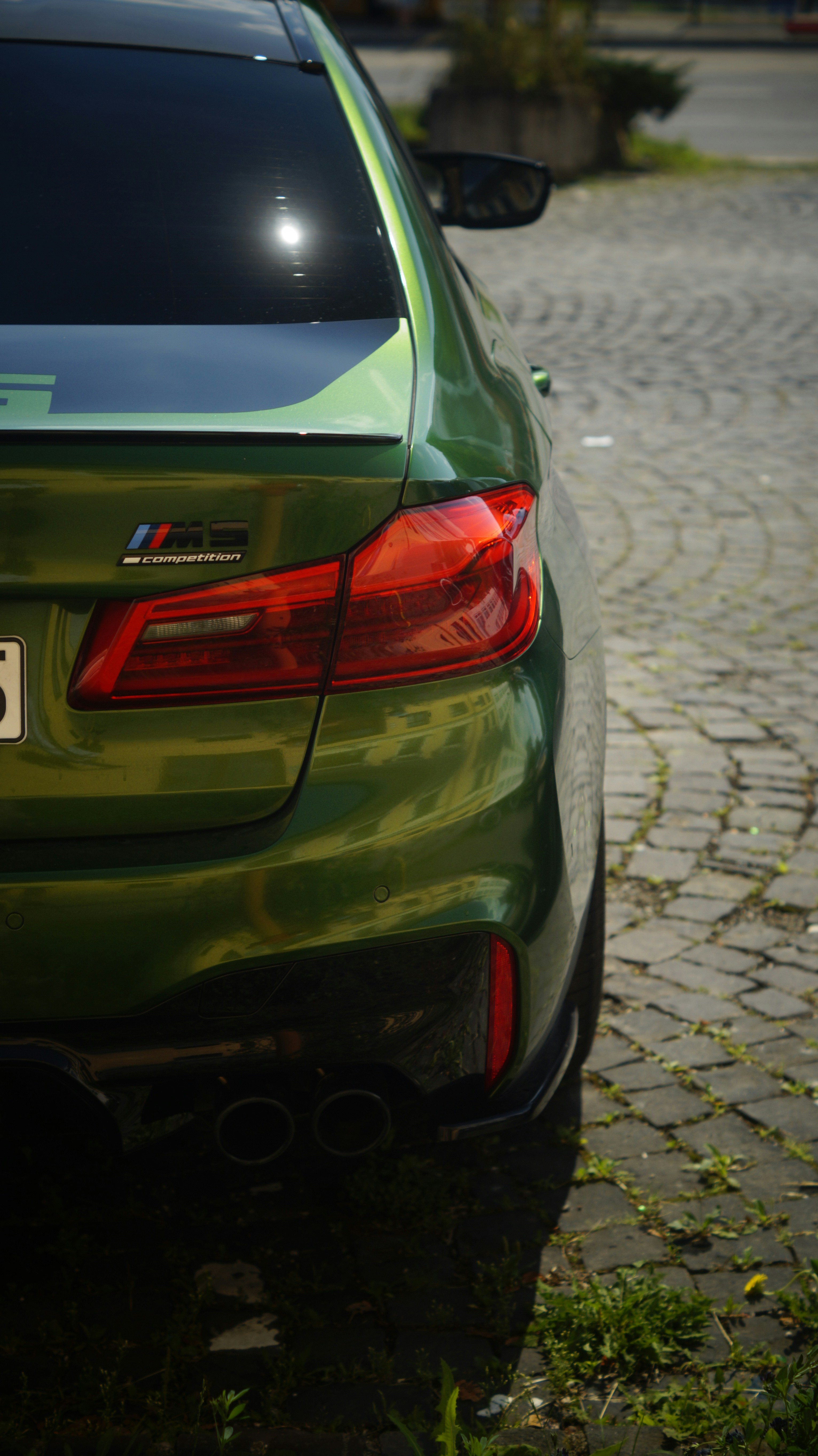 A green car parked on a cobblestone street