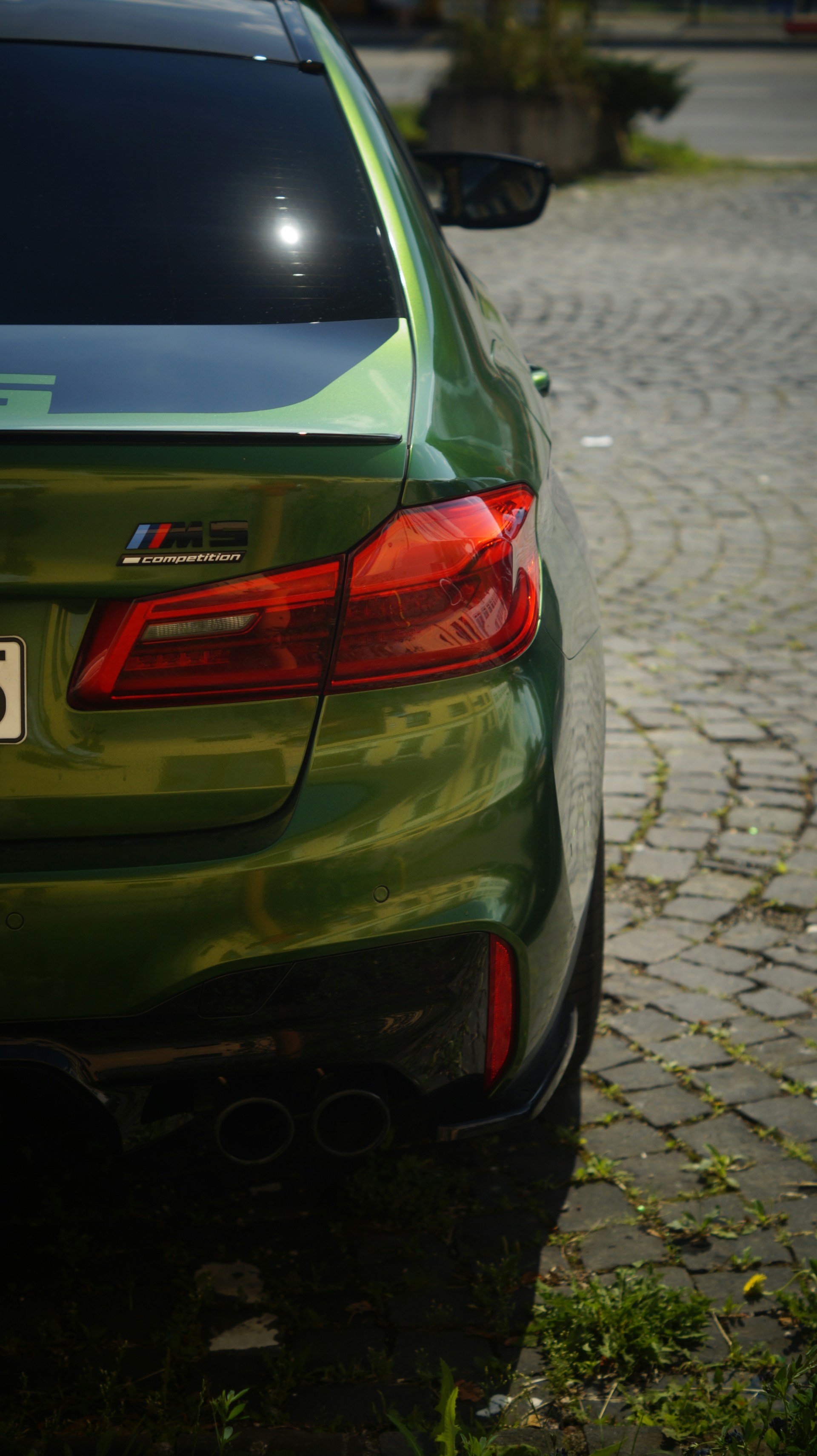 A green car parked on a cobblestone street