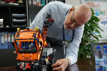 A man looking at a lego robot on a table