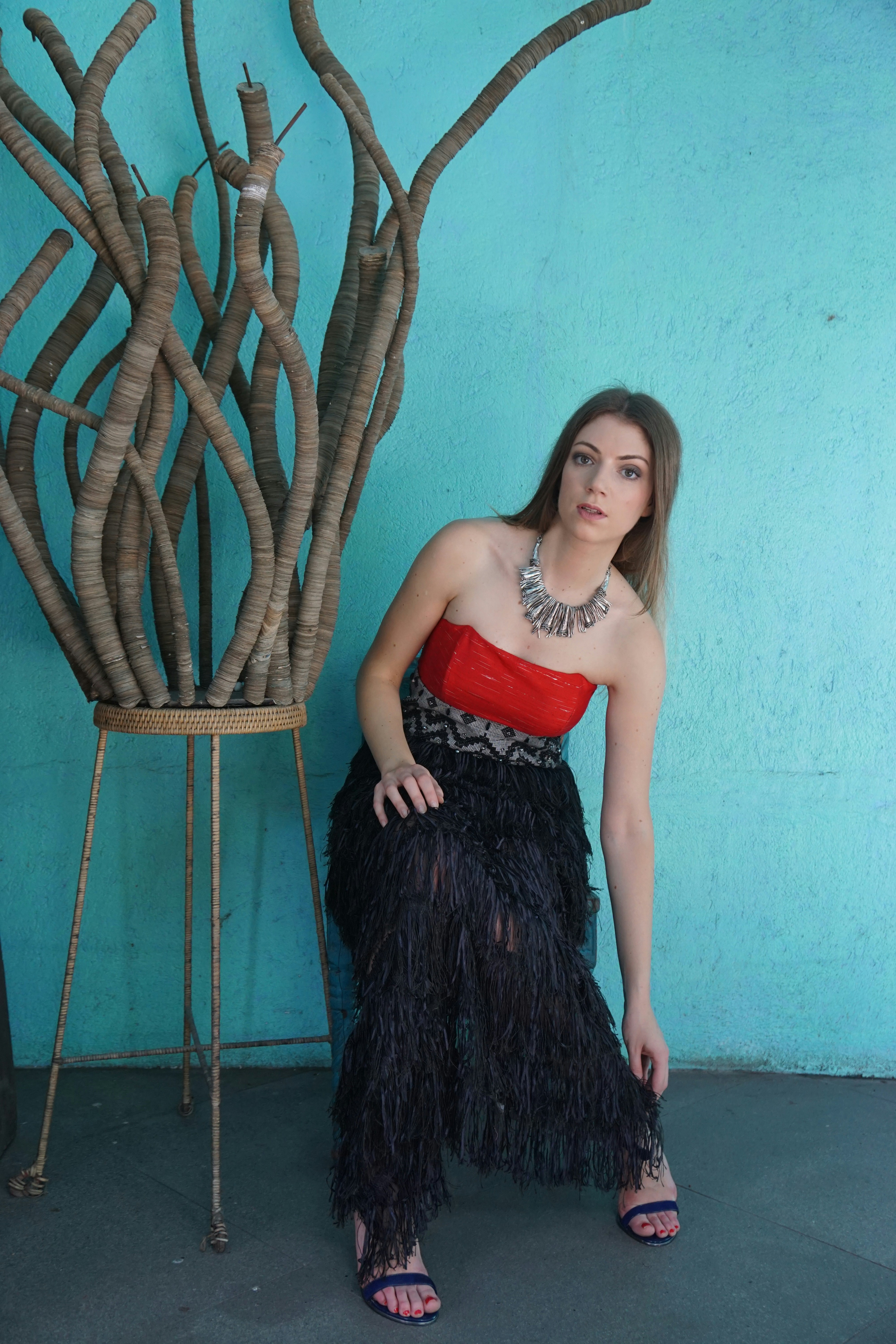 A woman in a red and black dress sitting on a chair photo – Free Model ...