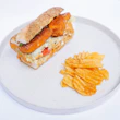 A white plate topped with a sandwich and chips