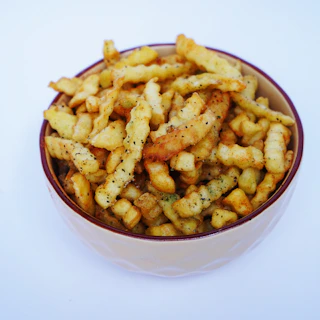 A white bowl filled with french fries on top of a table