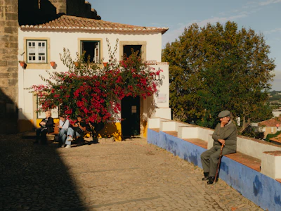 A man sitting on a ledge in front of a house