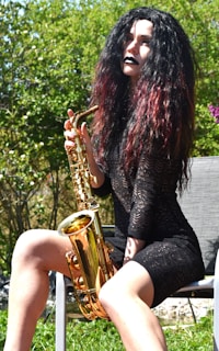 A woman sitting on a chair playing a saxophone