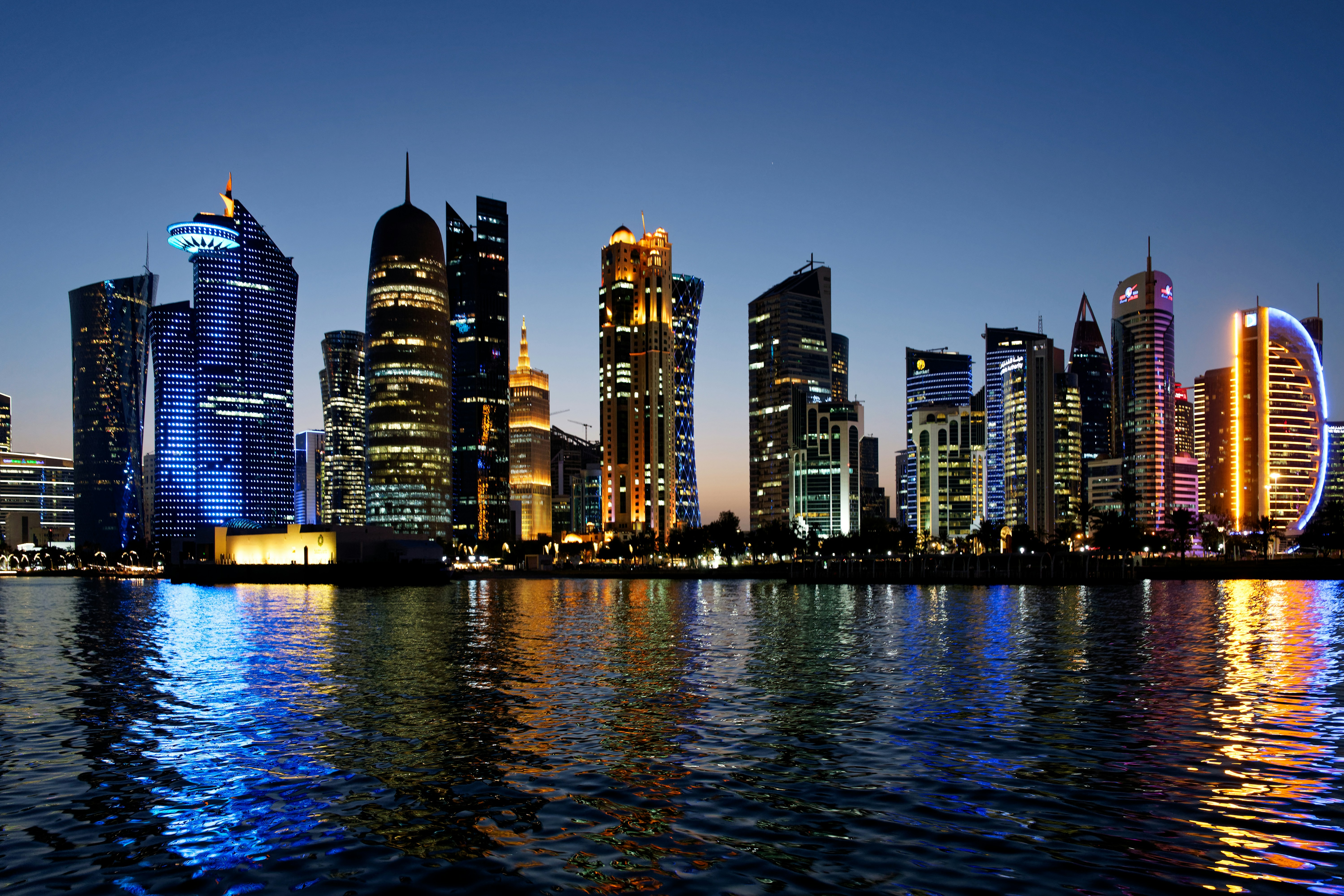 A nightscape of the city of Doha in Qatar with reflections in the sea.
