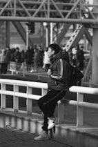 A man sitting on a rail near a crowd of people