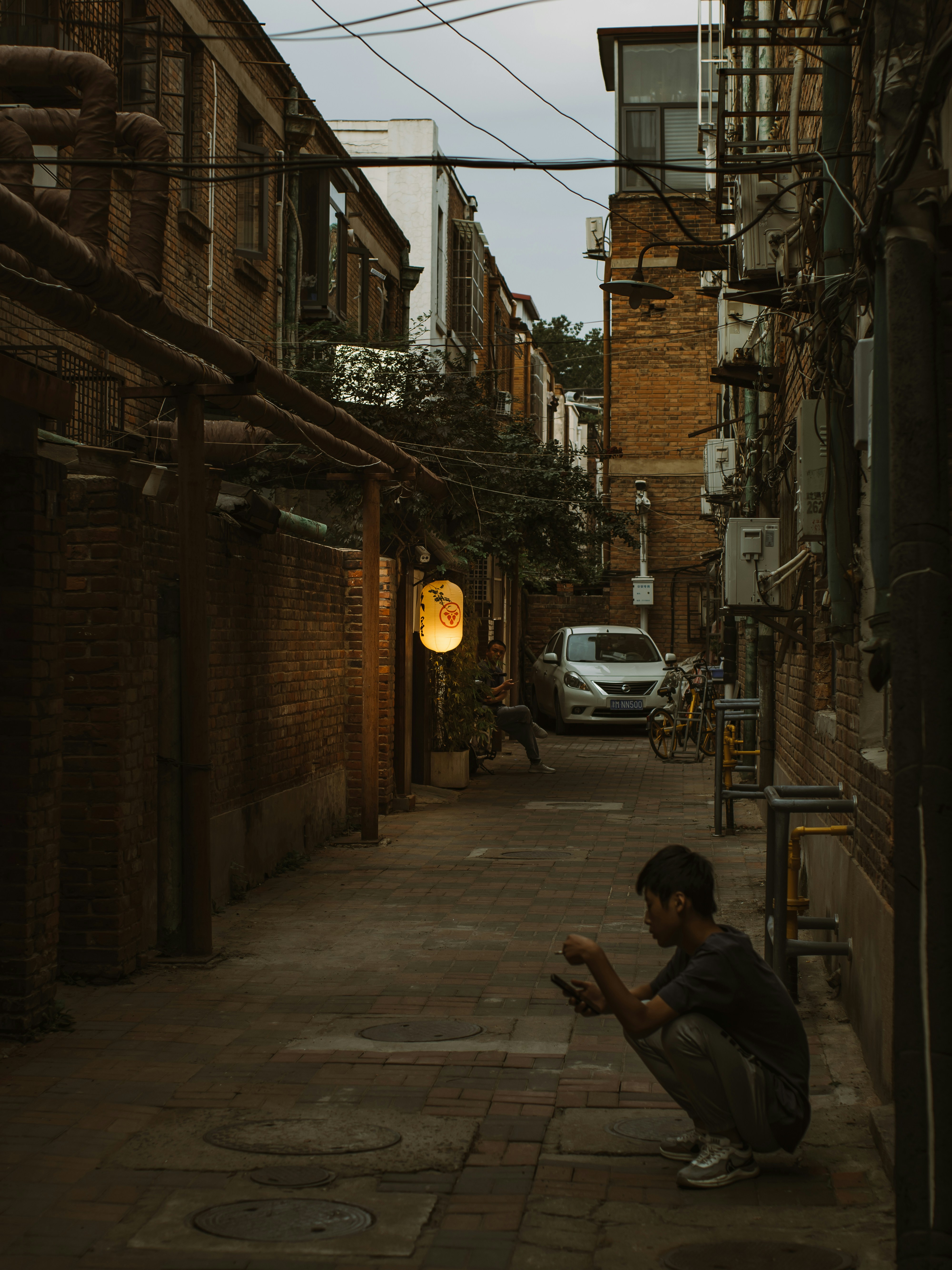 A man squatting down in an alley way