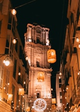 A city street at night with a clock tower in the background