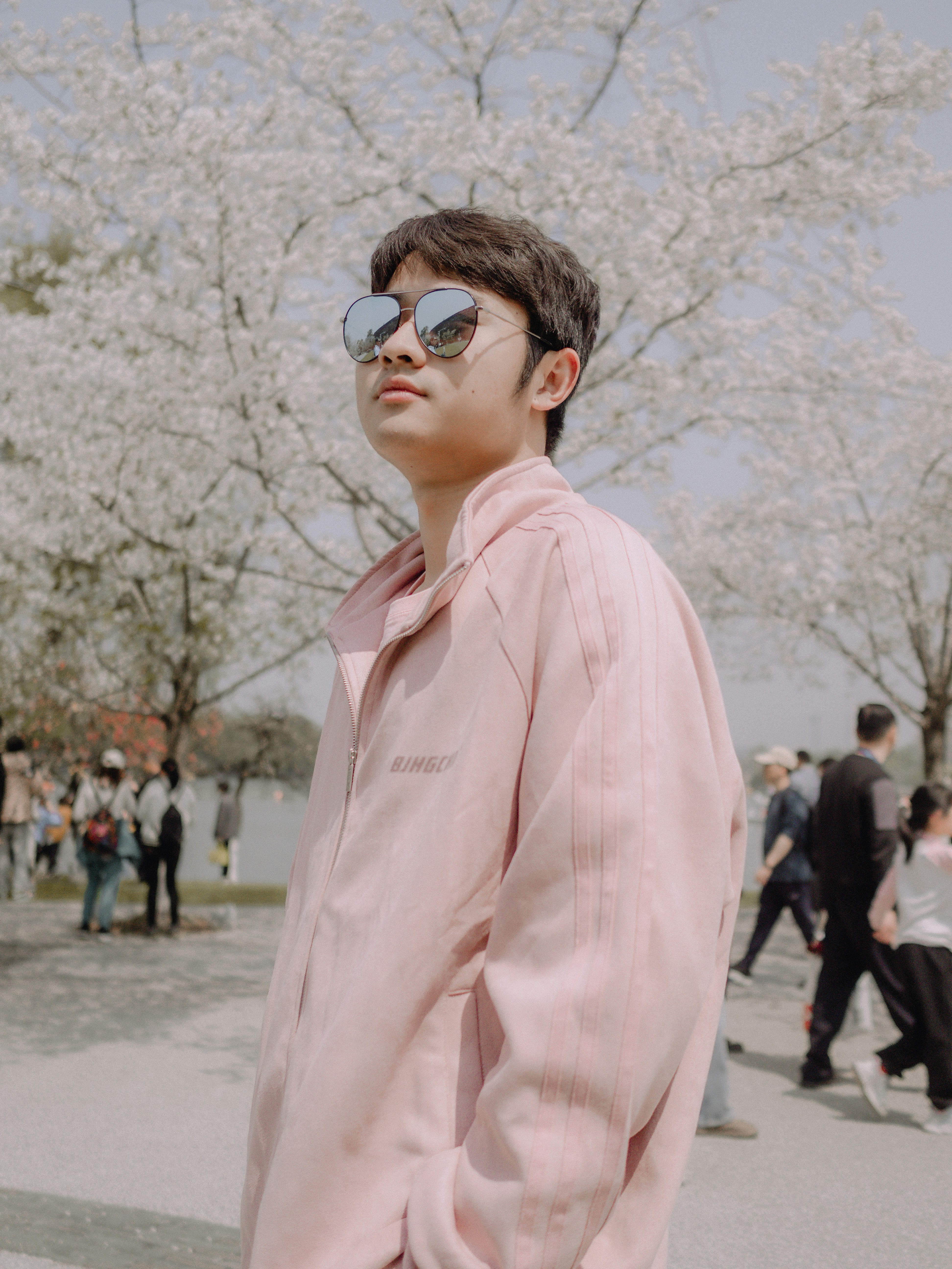 A man in a pink shirt standing in front of a tree