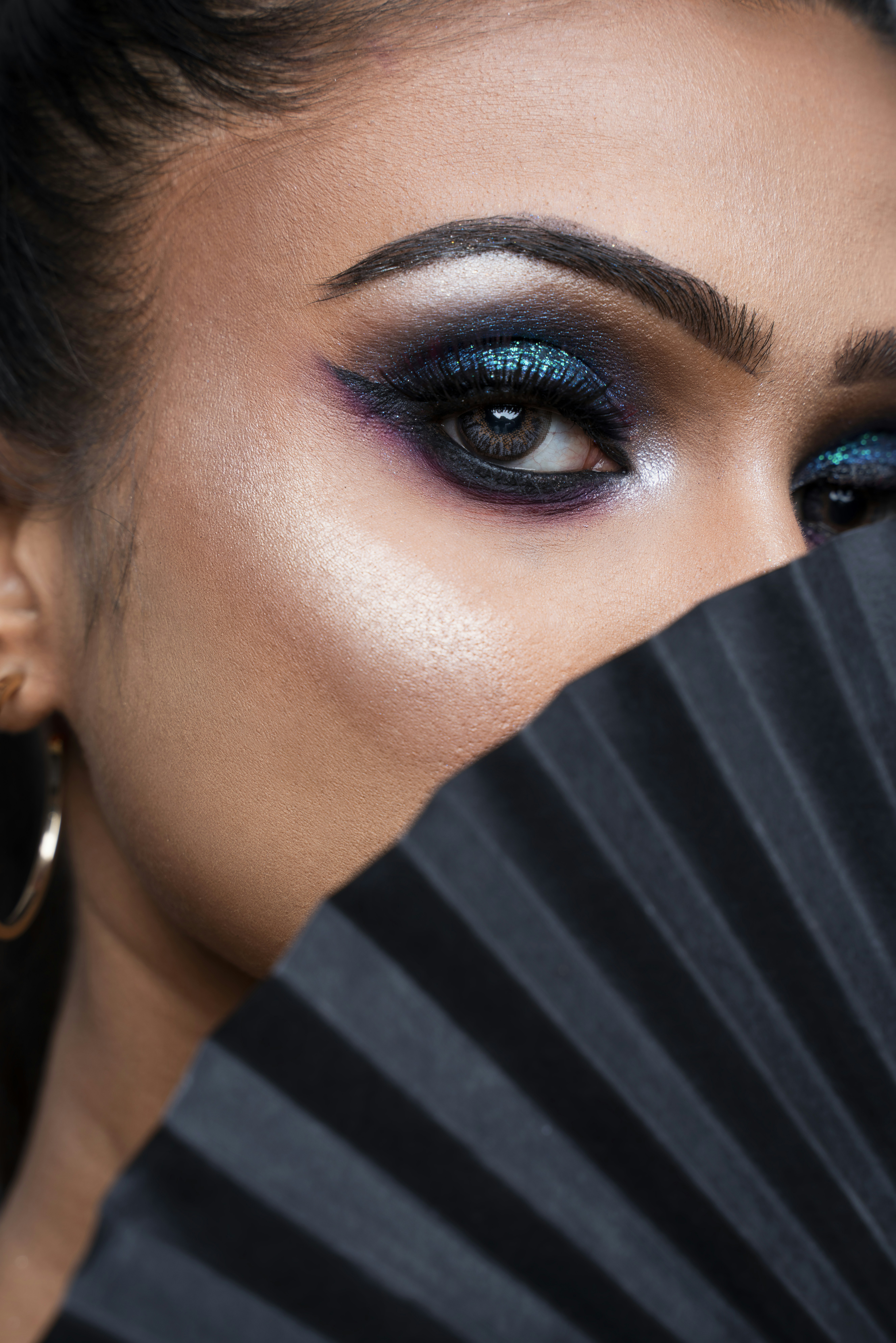 A woman with blue eyes and a black fan