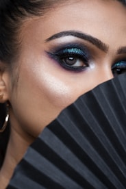 A woman with blue eyes and a black fan
