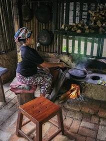 A woman sitting on a stool in front of a stove