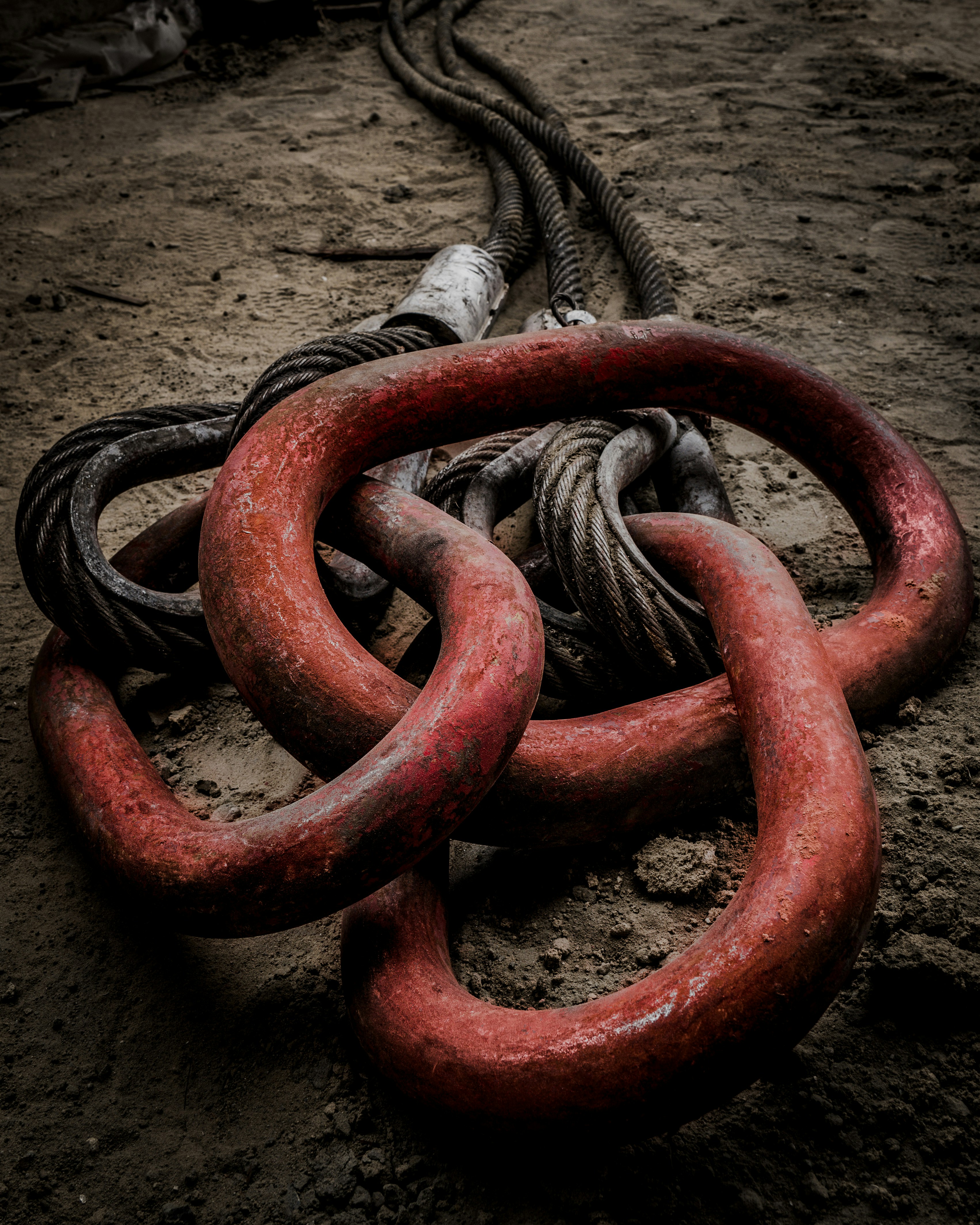 Un groupe de chaînes rouges posées sur un sol en terre battue