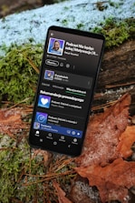 A cell phone sitting on top of a leaf covered ground