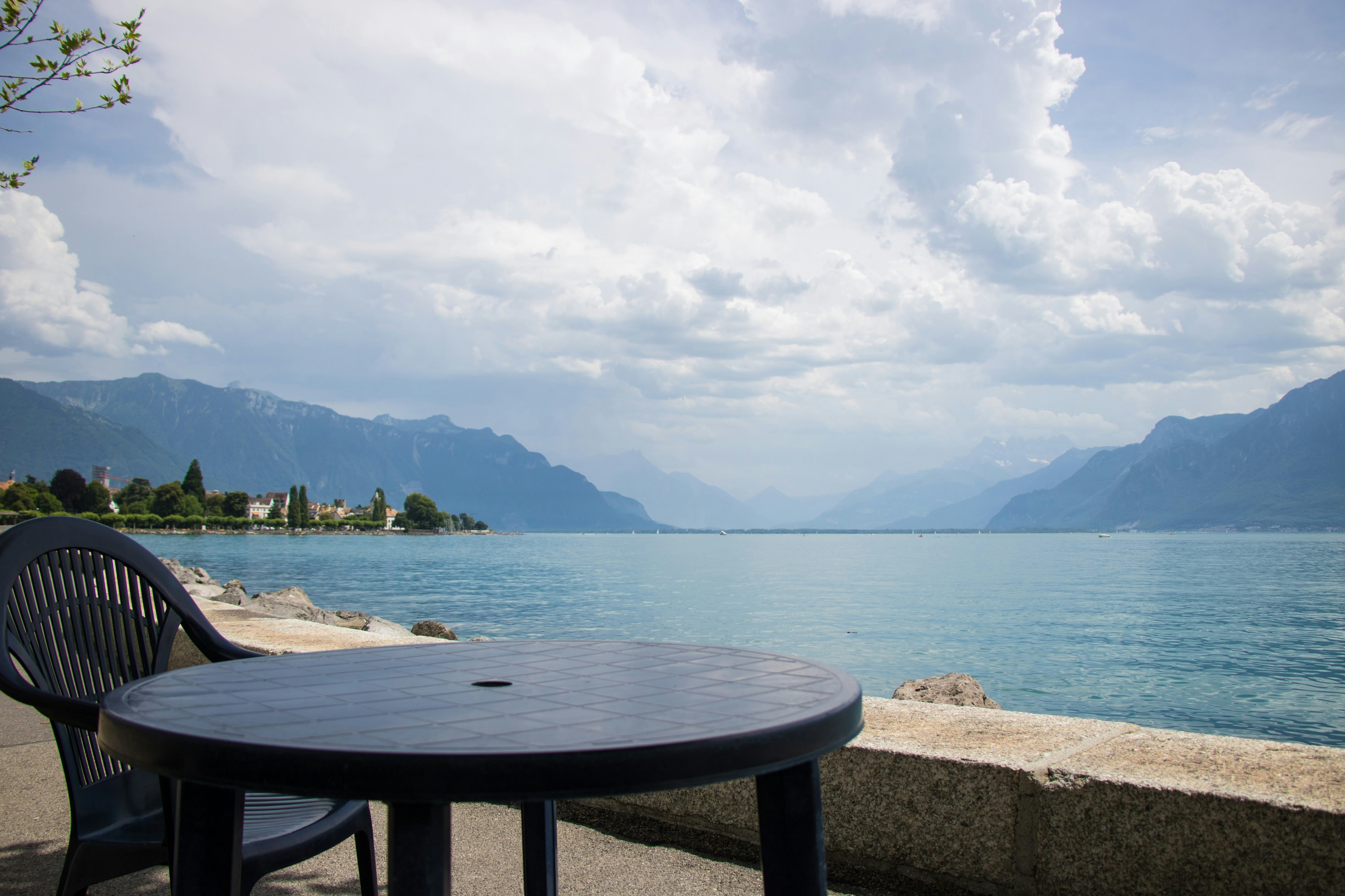 A table and chairs sitting on the side of a body of water