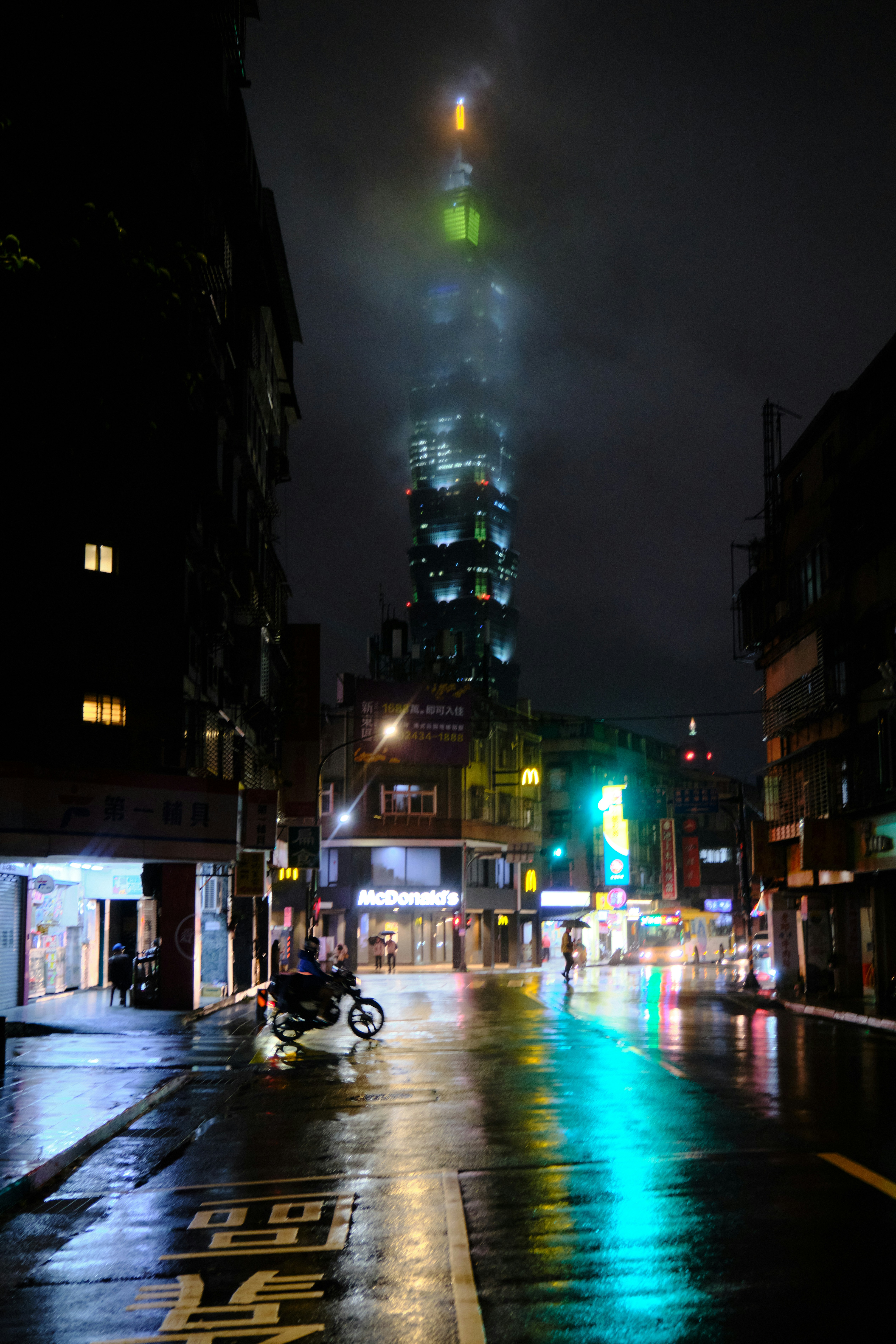 A city street at night with a tall building in the background