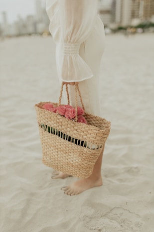 A woman standing on a beach holding a basket of flowers