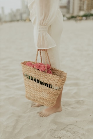 A woman standing on a beach holding a basket of flowers