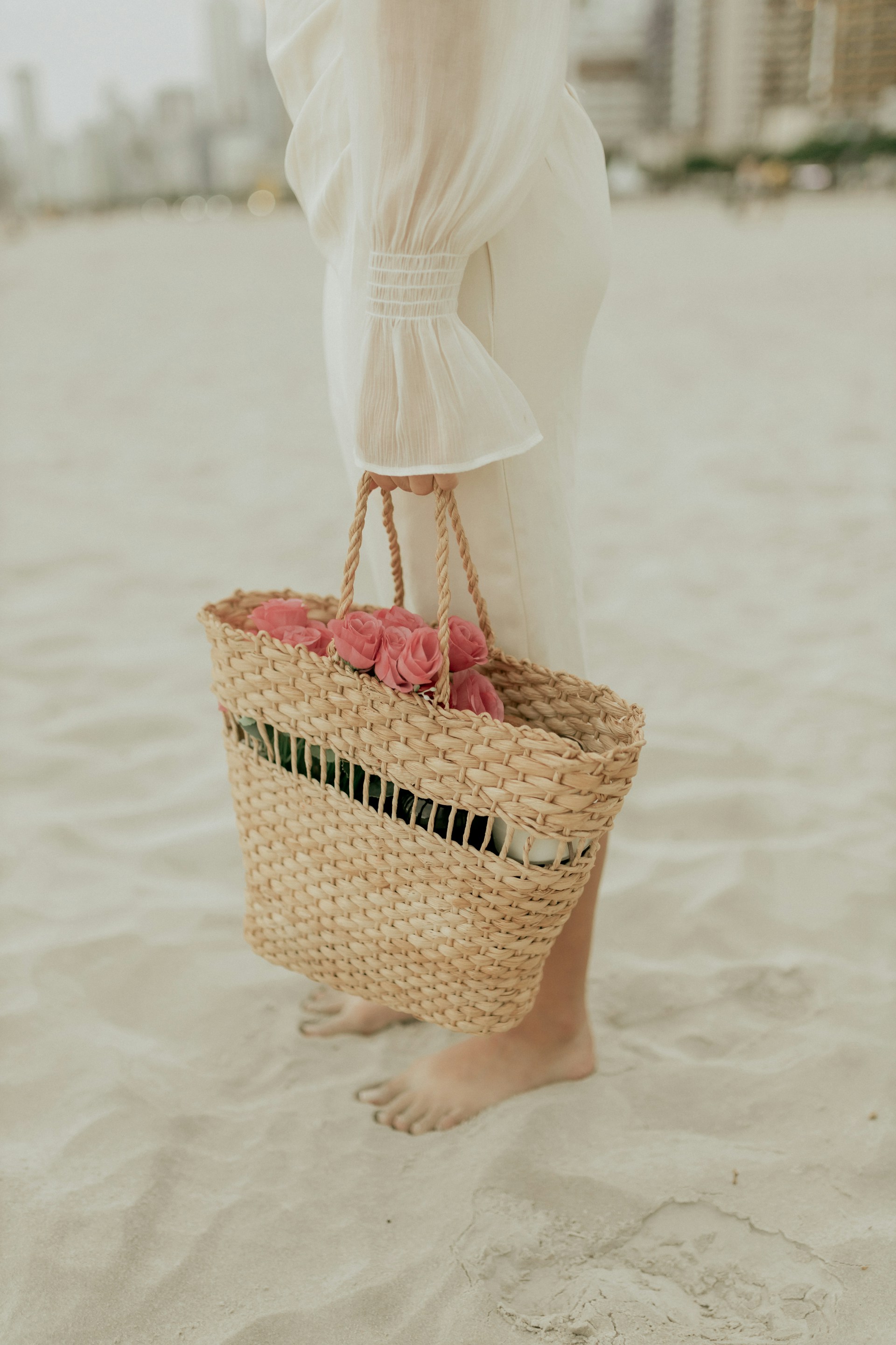 A woman standing on a beach holding a basket of flowers