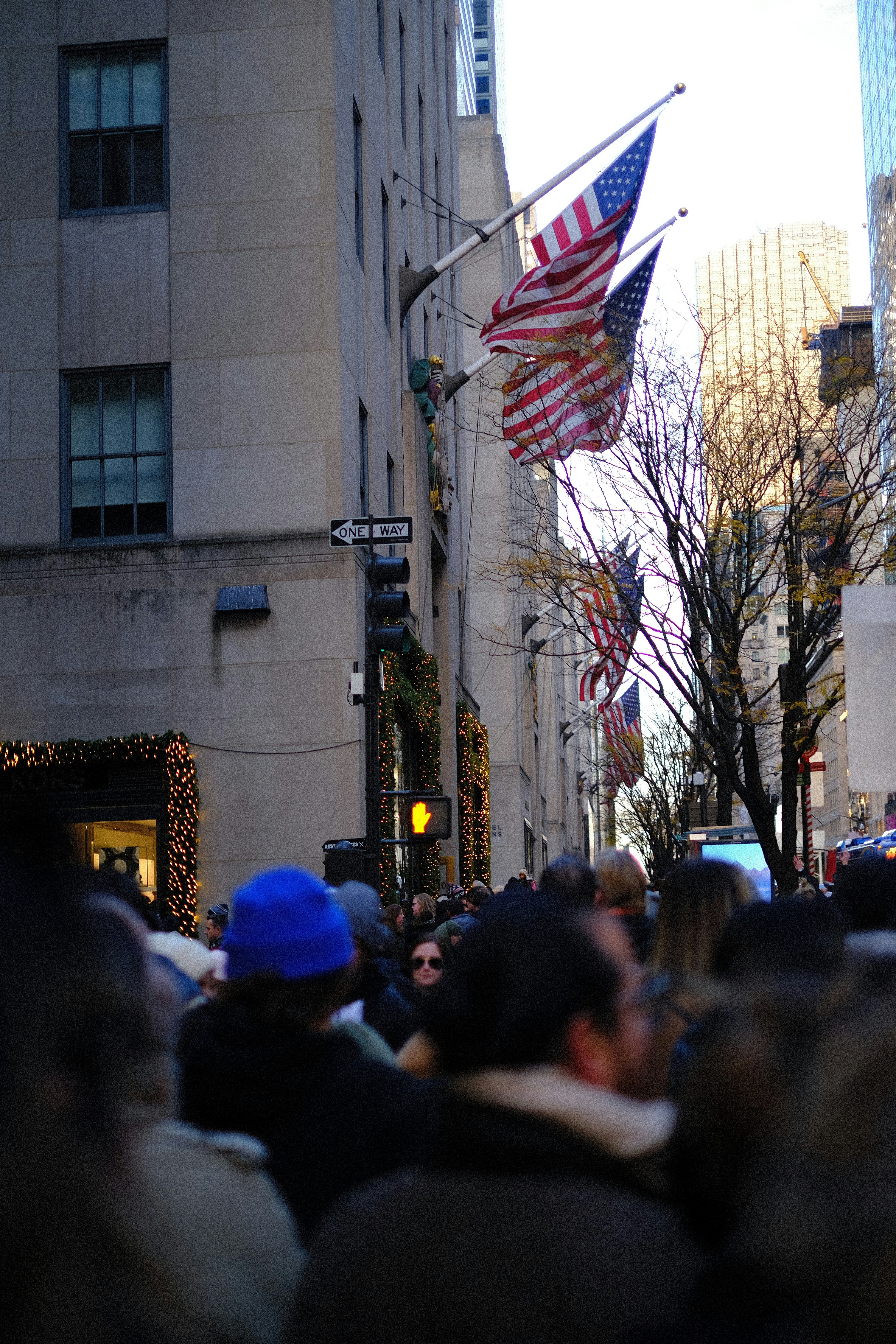 A crowd of people walking down a street next to tall buildings