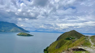 A large body of water sitting next to a lush green hillside