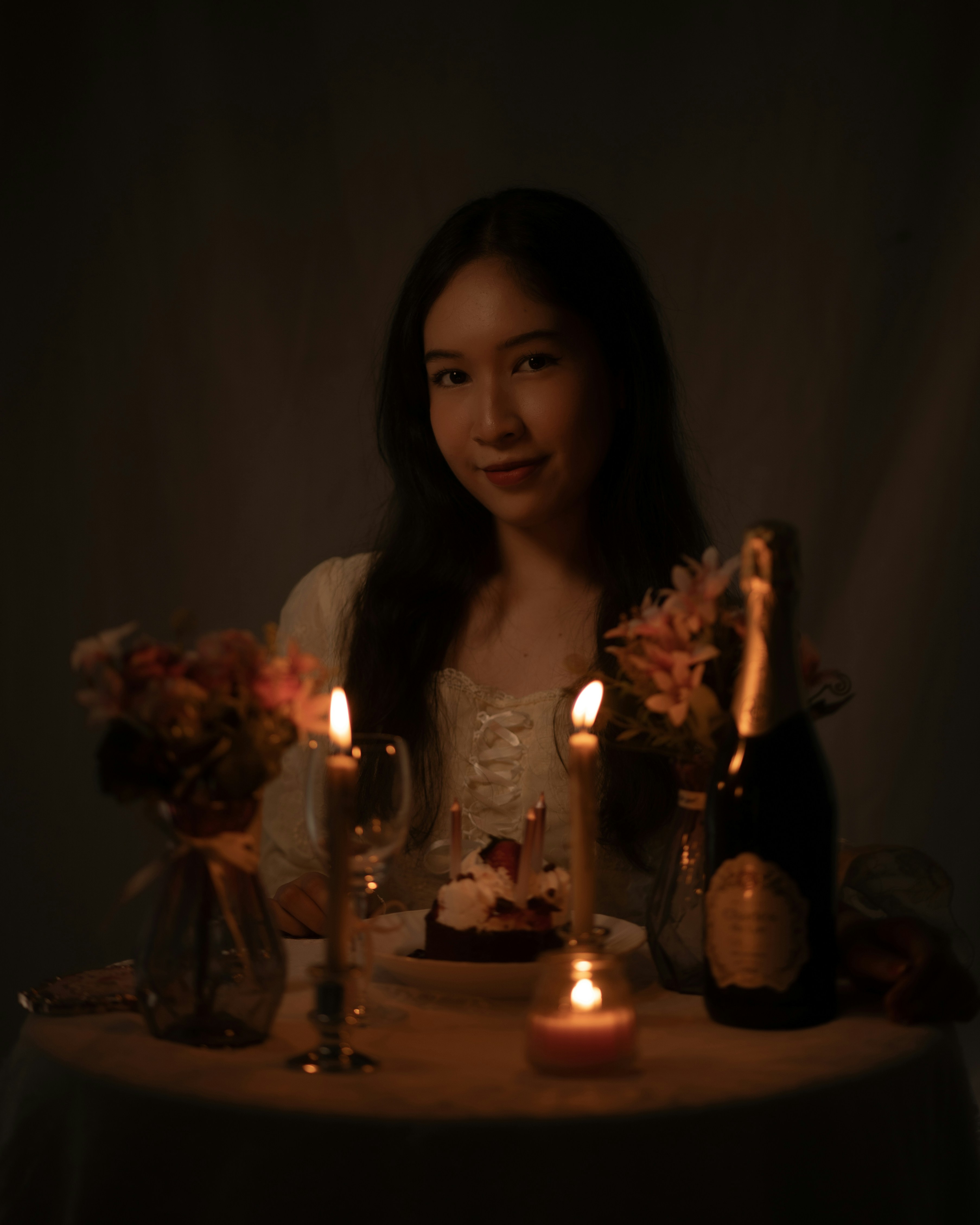 Seorang wanita duduk di meja dengan lilin di depannya