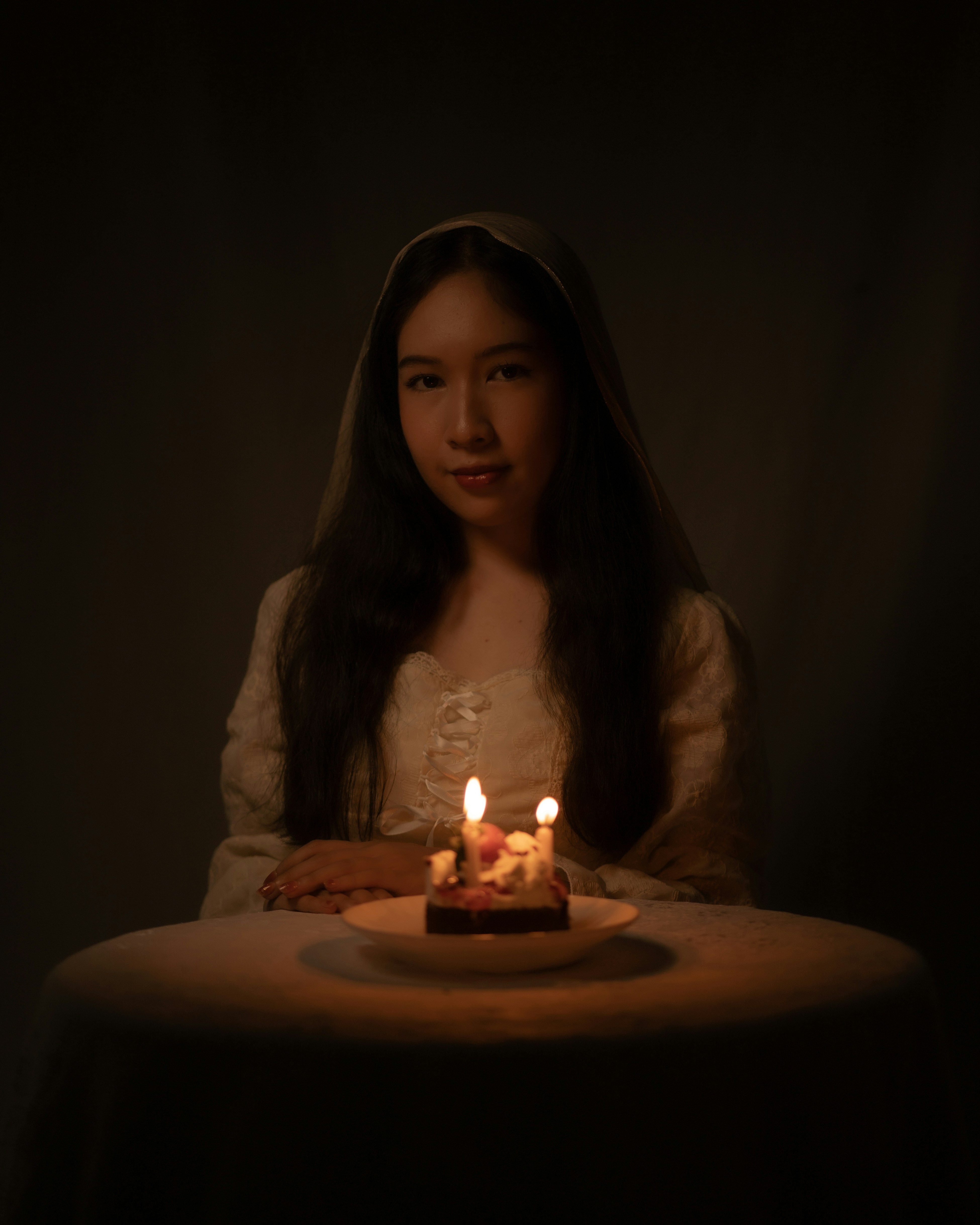 A woman sitting in front of a cake with lit candles