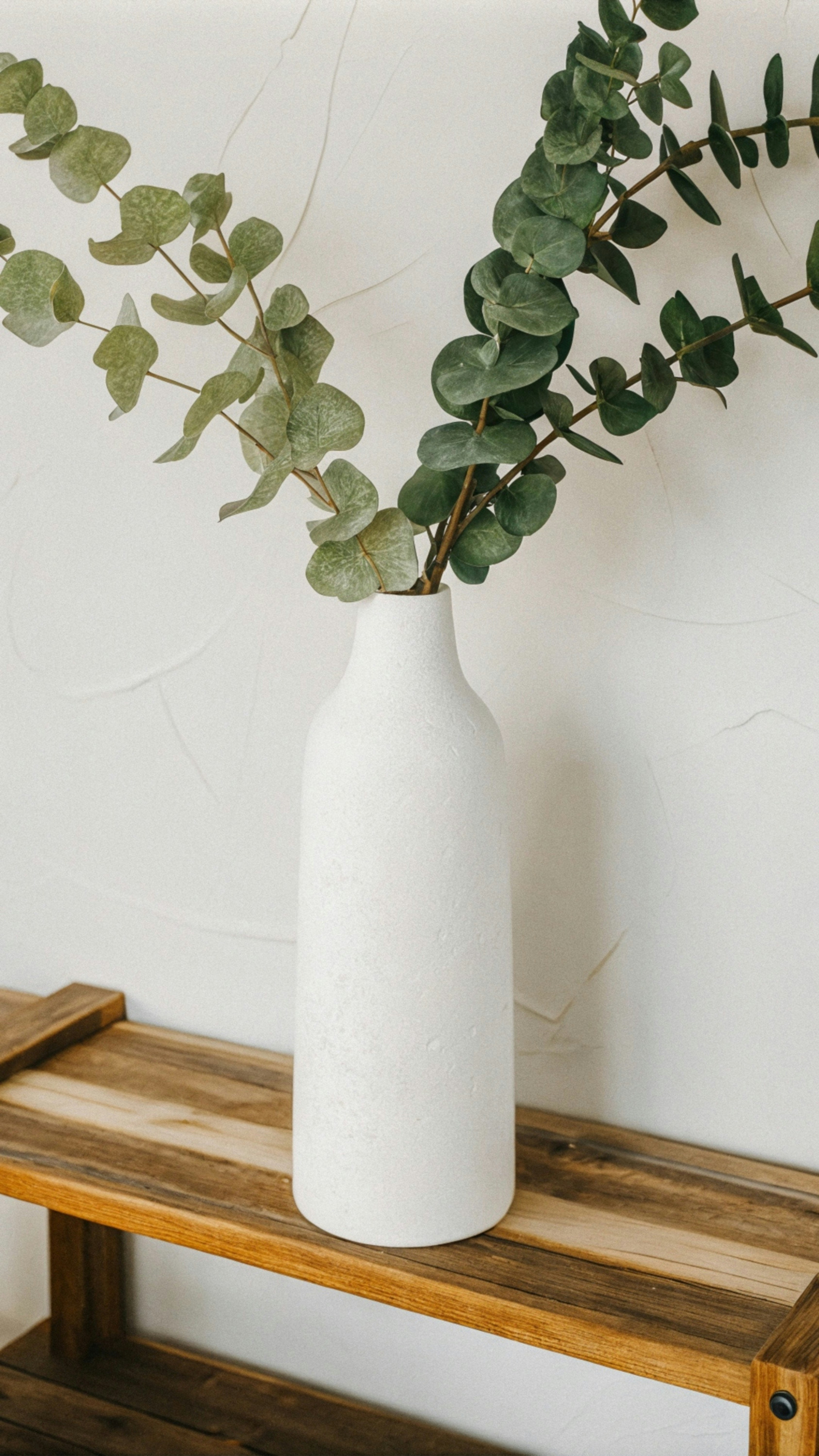 Eine weiße Vase, die auf einem Holzregal sitzt