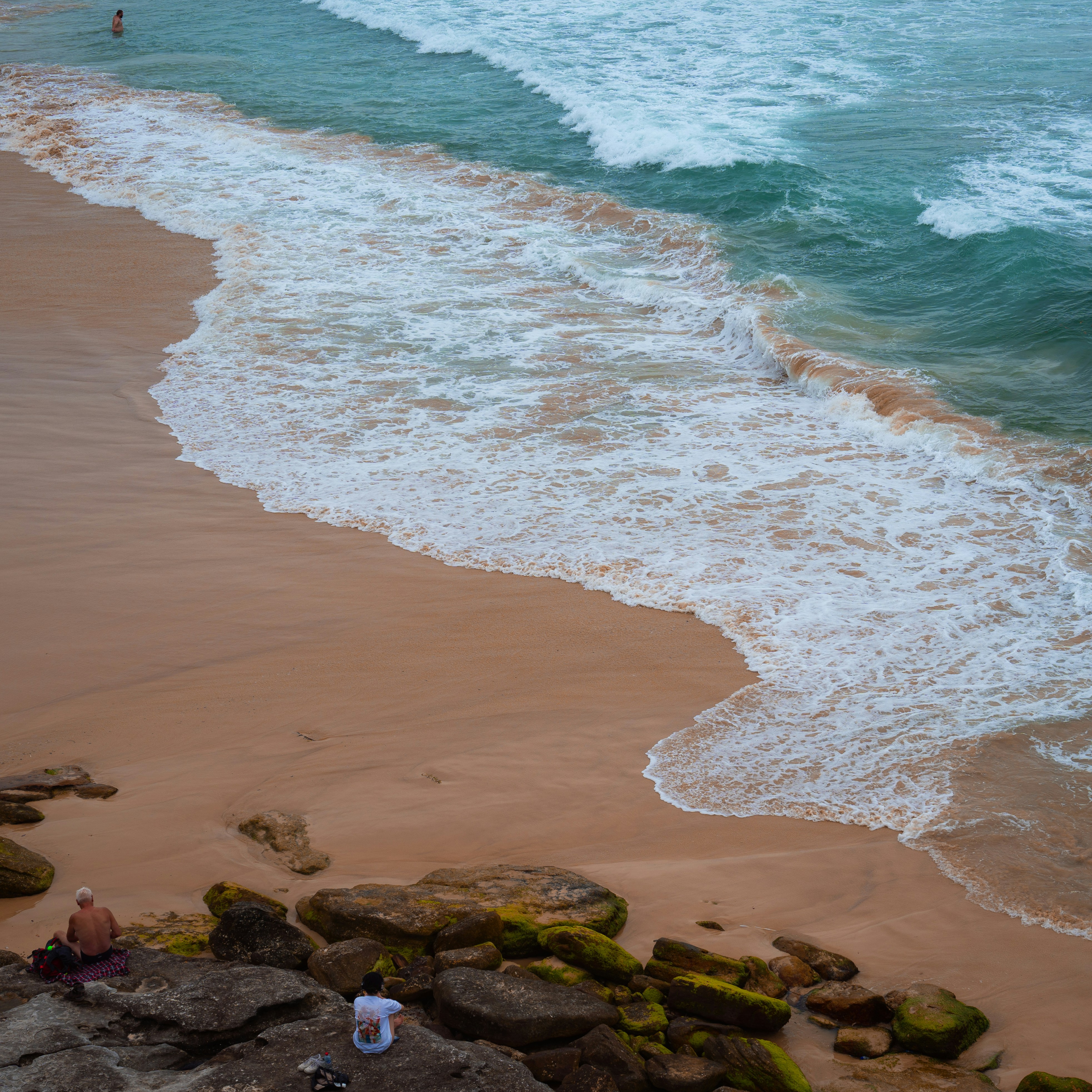 Quelques personnes debout au sommet d’une plage à côté de l’océan
