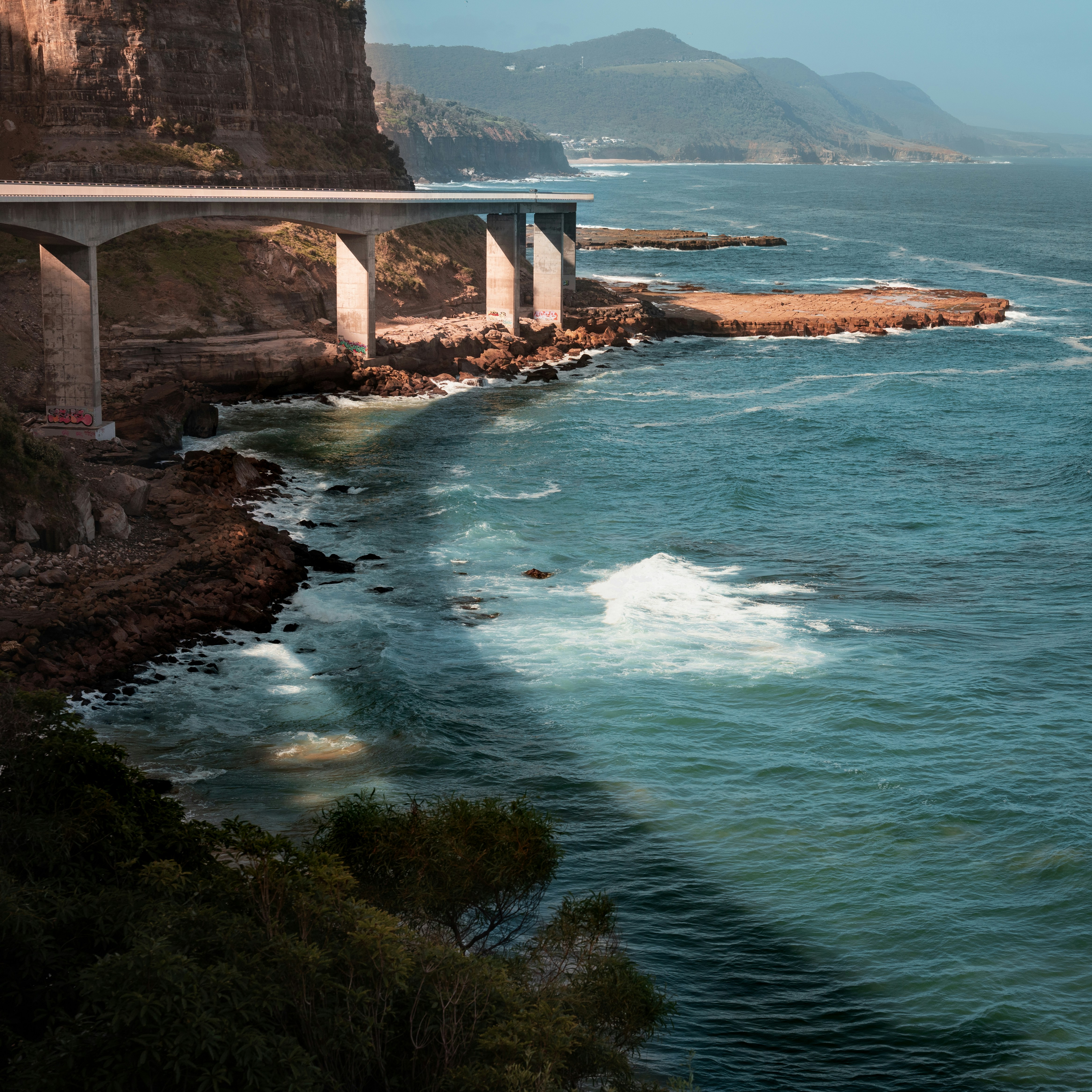 Un pont au-dessus d’un plan d’eau à côté d’une falaise