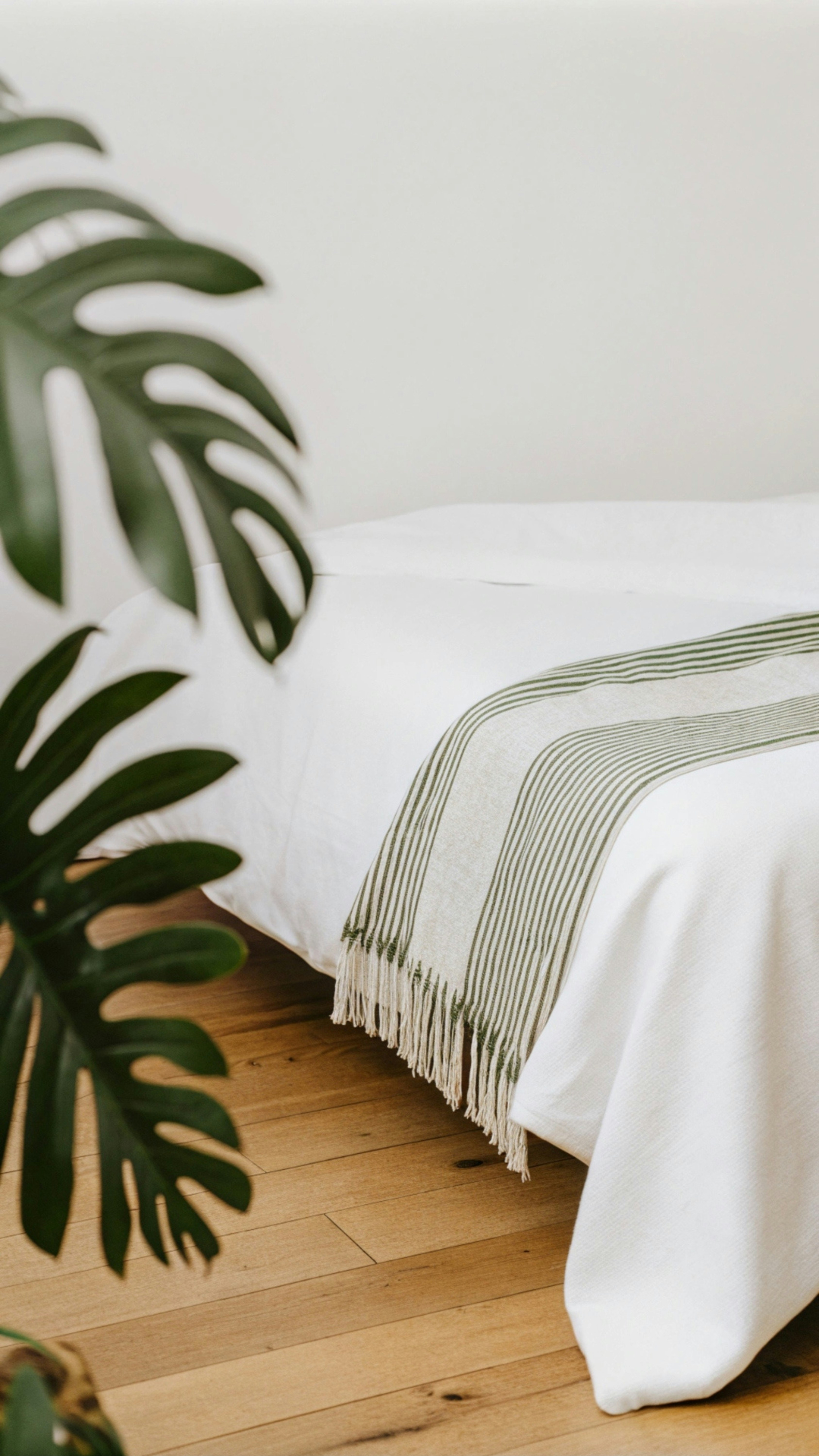 Ein weißes Bett mit einer grün-weißen Decke