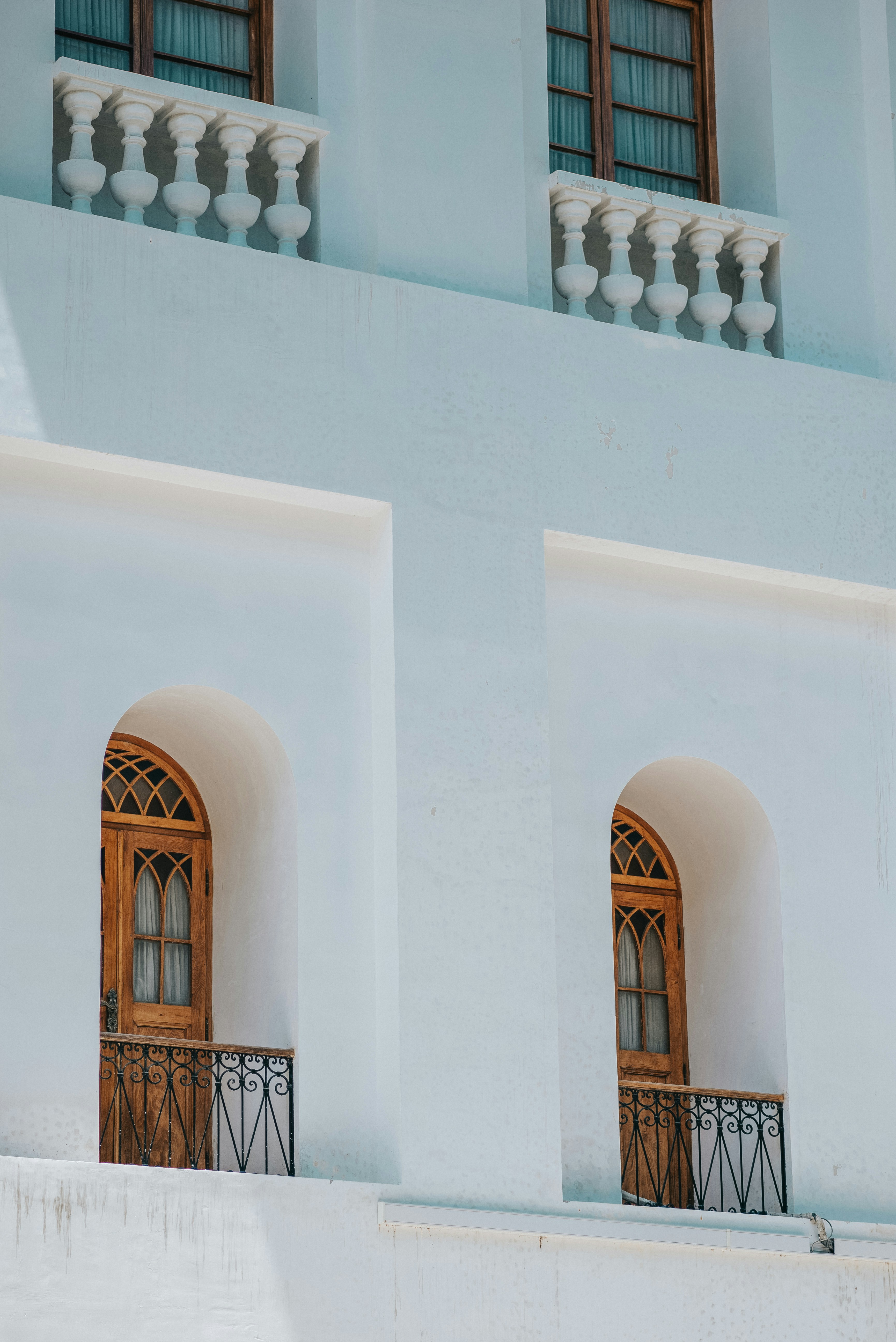 A white building with two windows and a balcony