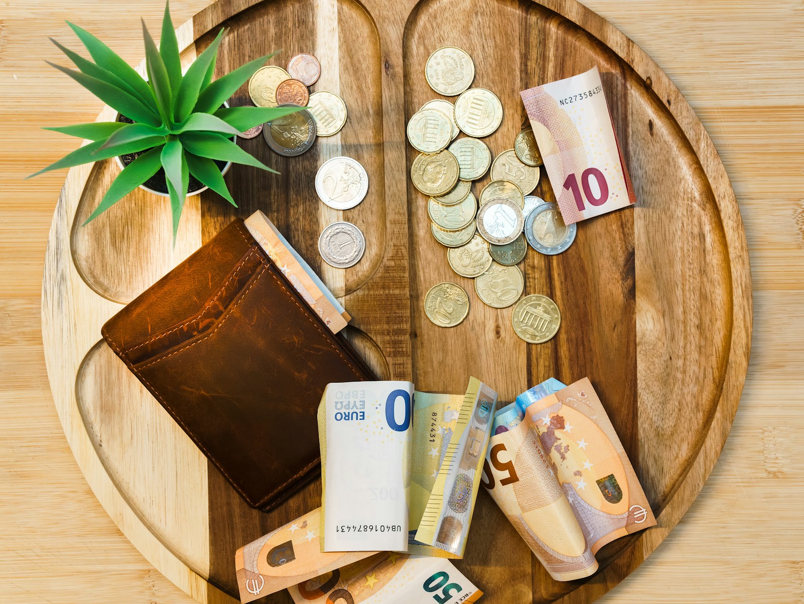 Moedas e notas de dinheiro sobre mesa de madeira