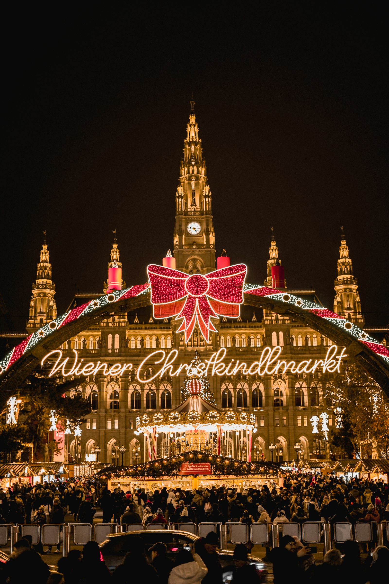 Vienna's City Hall lit up behind the glowing bow-topped arch of the Christmas market at Rathausplatz