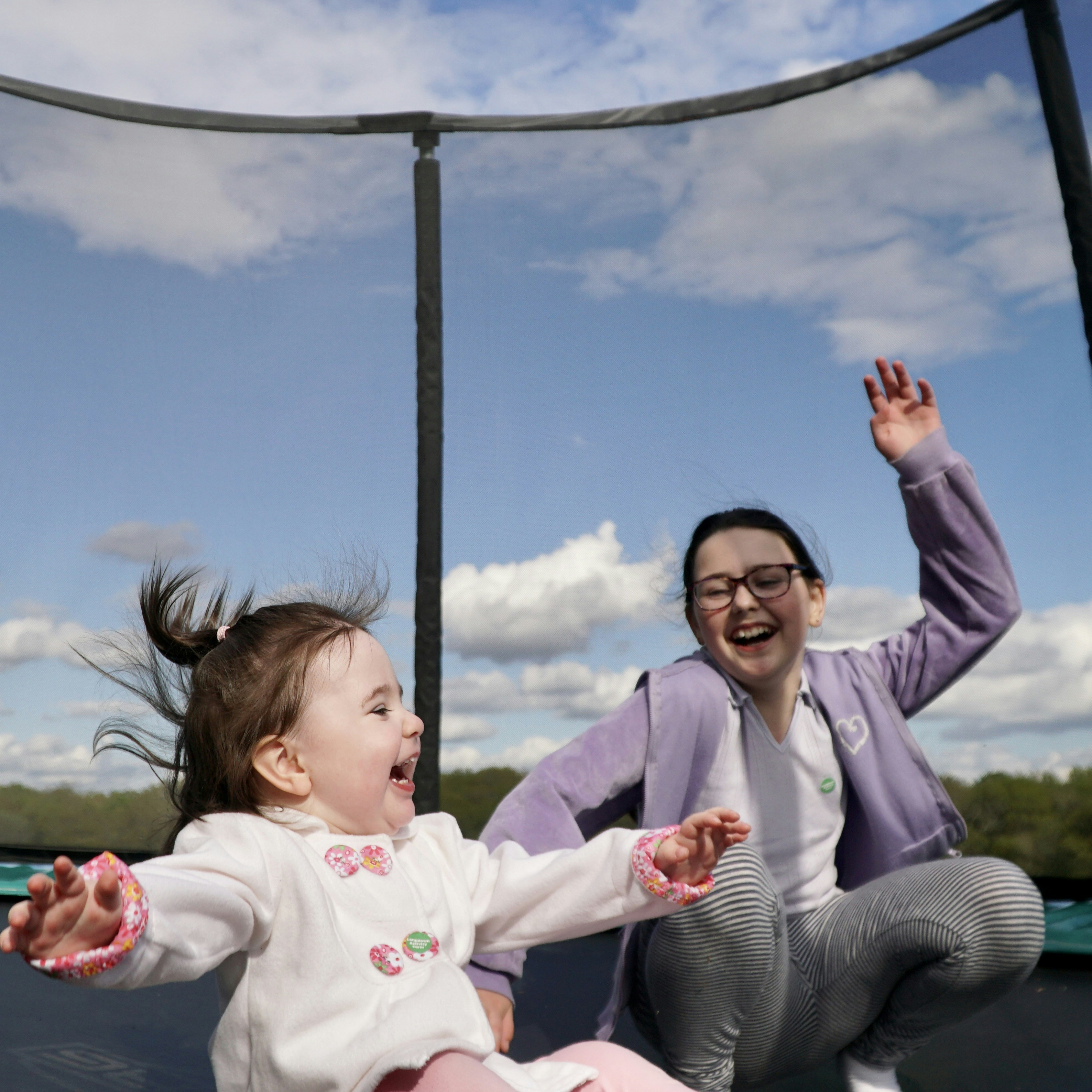 A woman and a child playing on a trampoline